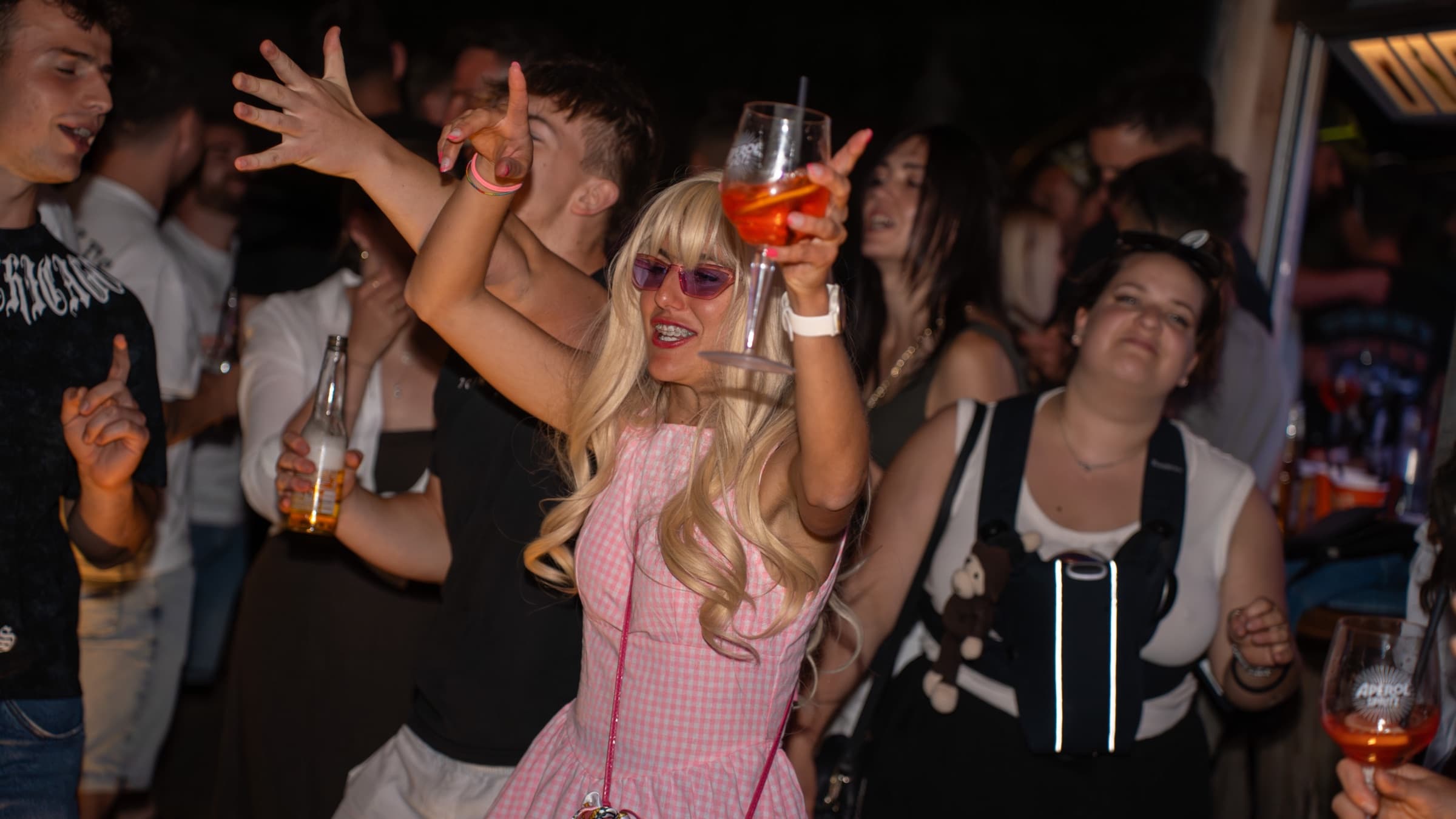 Serata di apertura del chiosco Bar Alla Spiaggia, con gente che balla e brinda tra le luci notturne