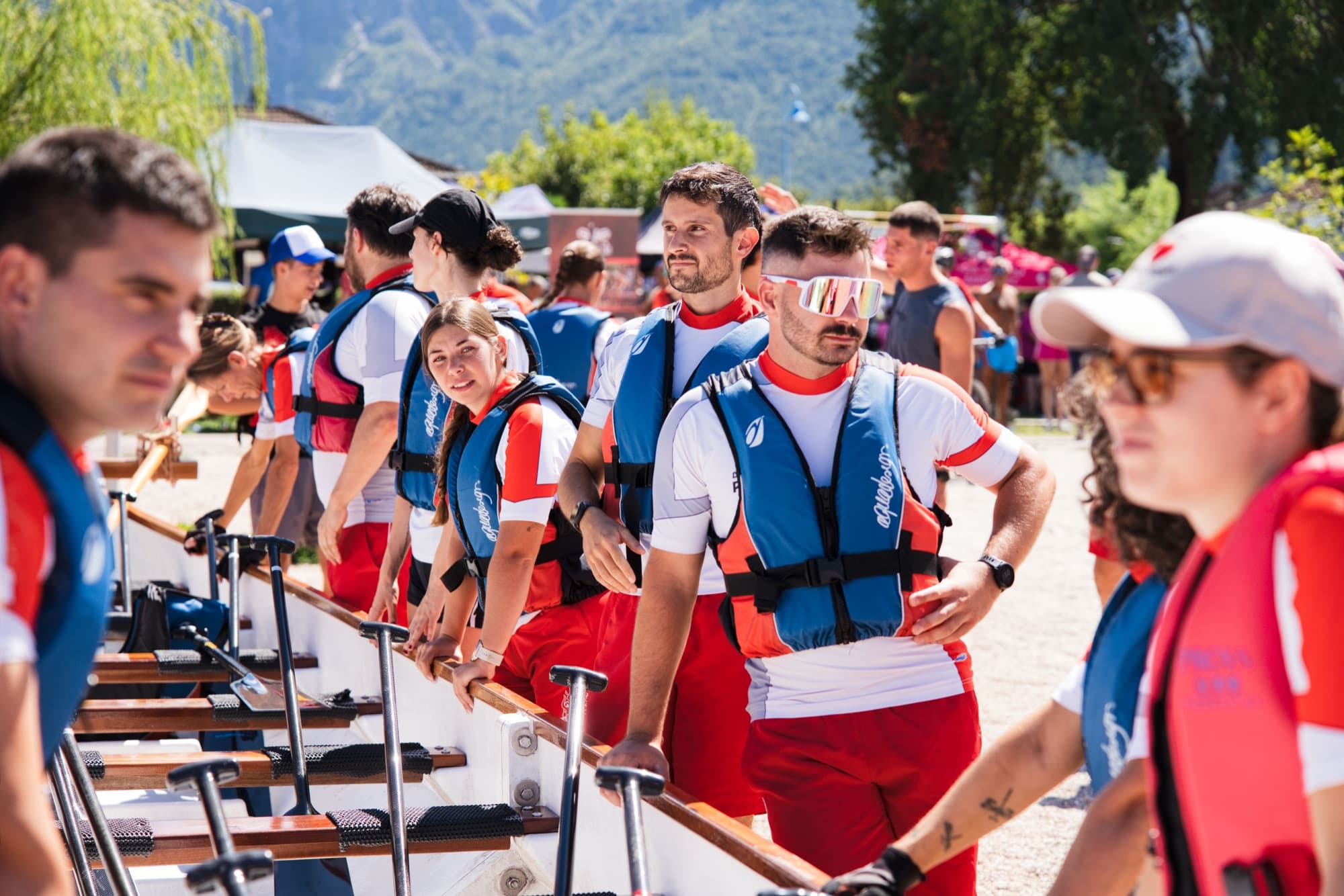 Un equipaggio di dragon boat in fila prima della partenza, con il lago e le montagne sullo sfondo