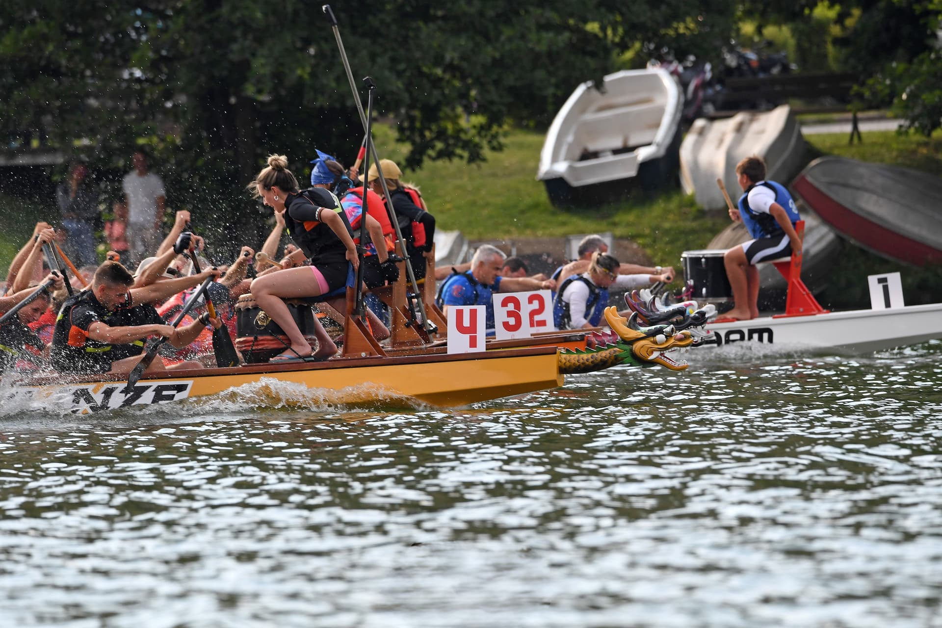 Due equipaggi di dragon boat affiancati in gara sul lago, con le pale che sollevano spruzzi d'acqua