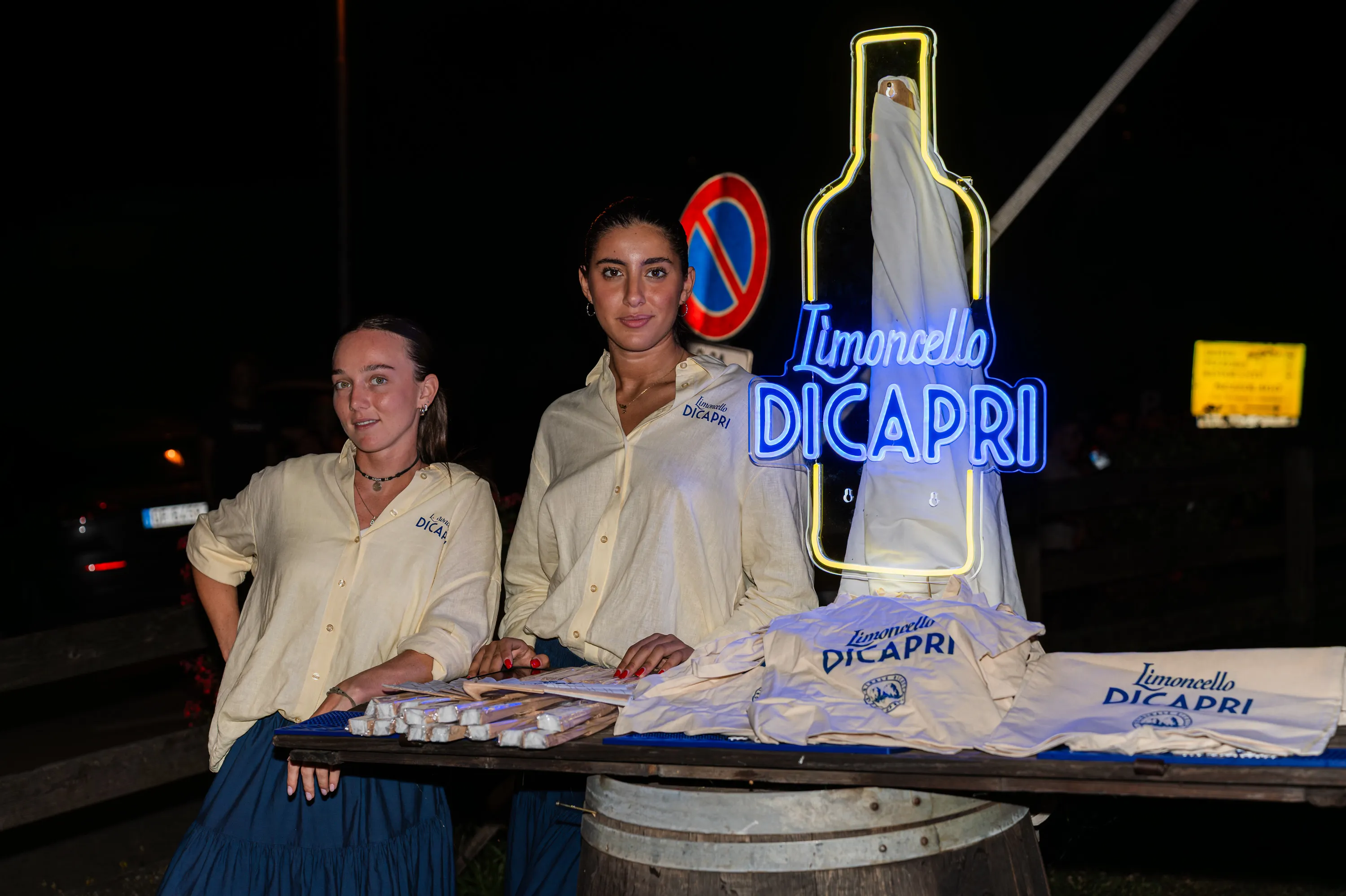 Due persone davanti al banco del Limoncello di Capri, con l'insegna accesa