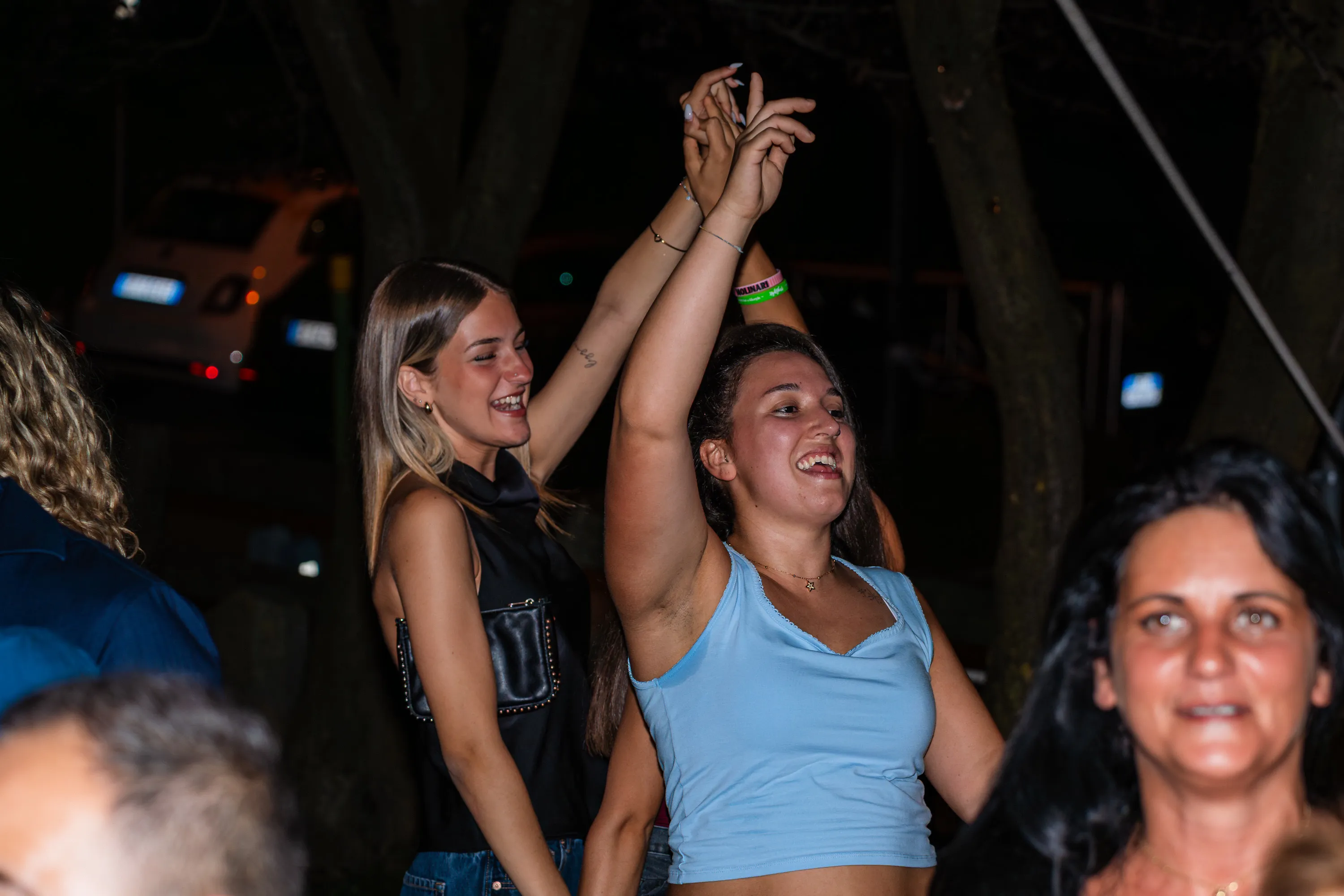 Tre donne ballano con le braccia alzate