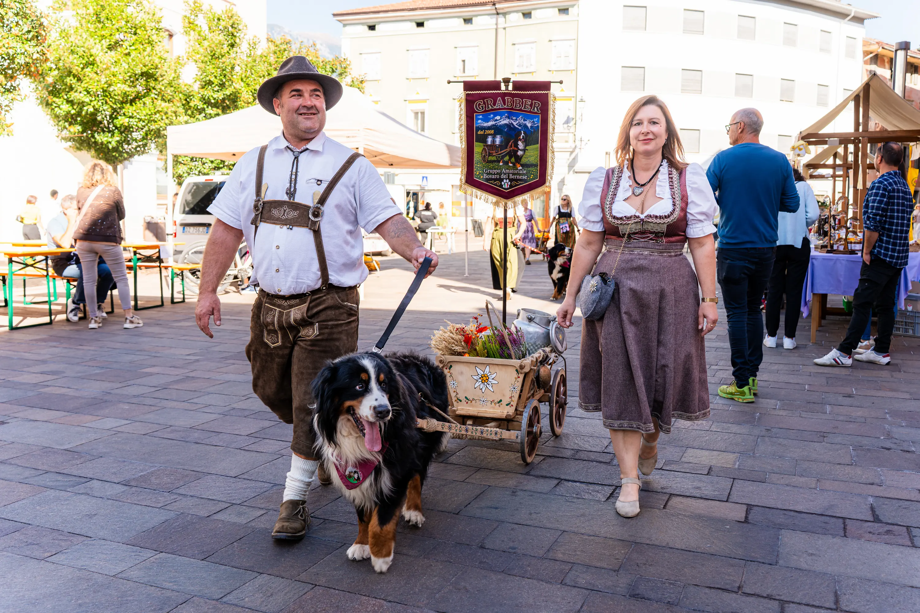 Un uomo in costume tradizionale con un bovaro del Bernese e un carretto, accanto a una donna in dirndl