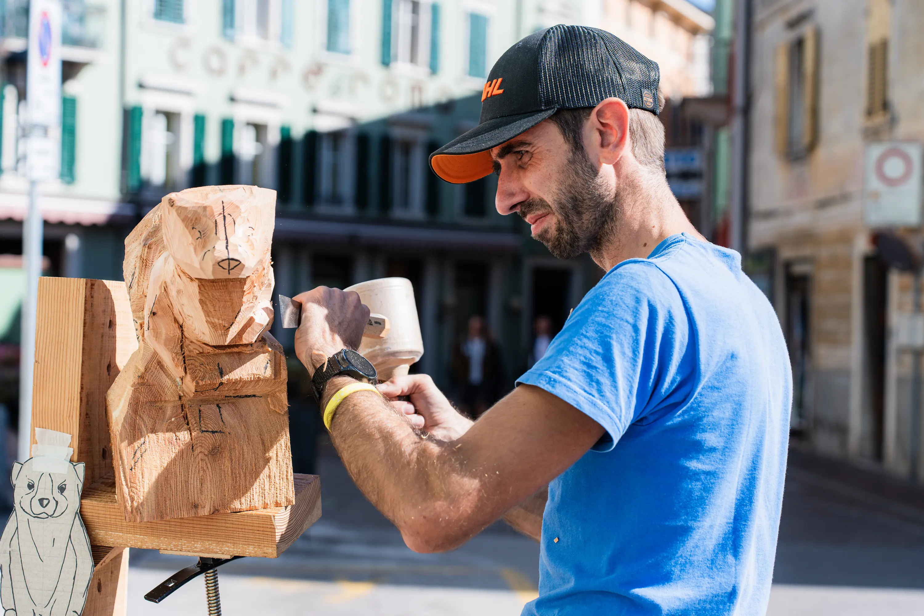 Un intagliatore lavora una scultura di legno lungo la via