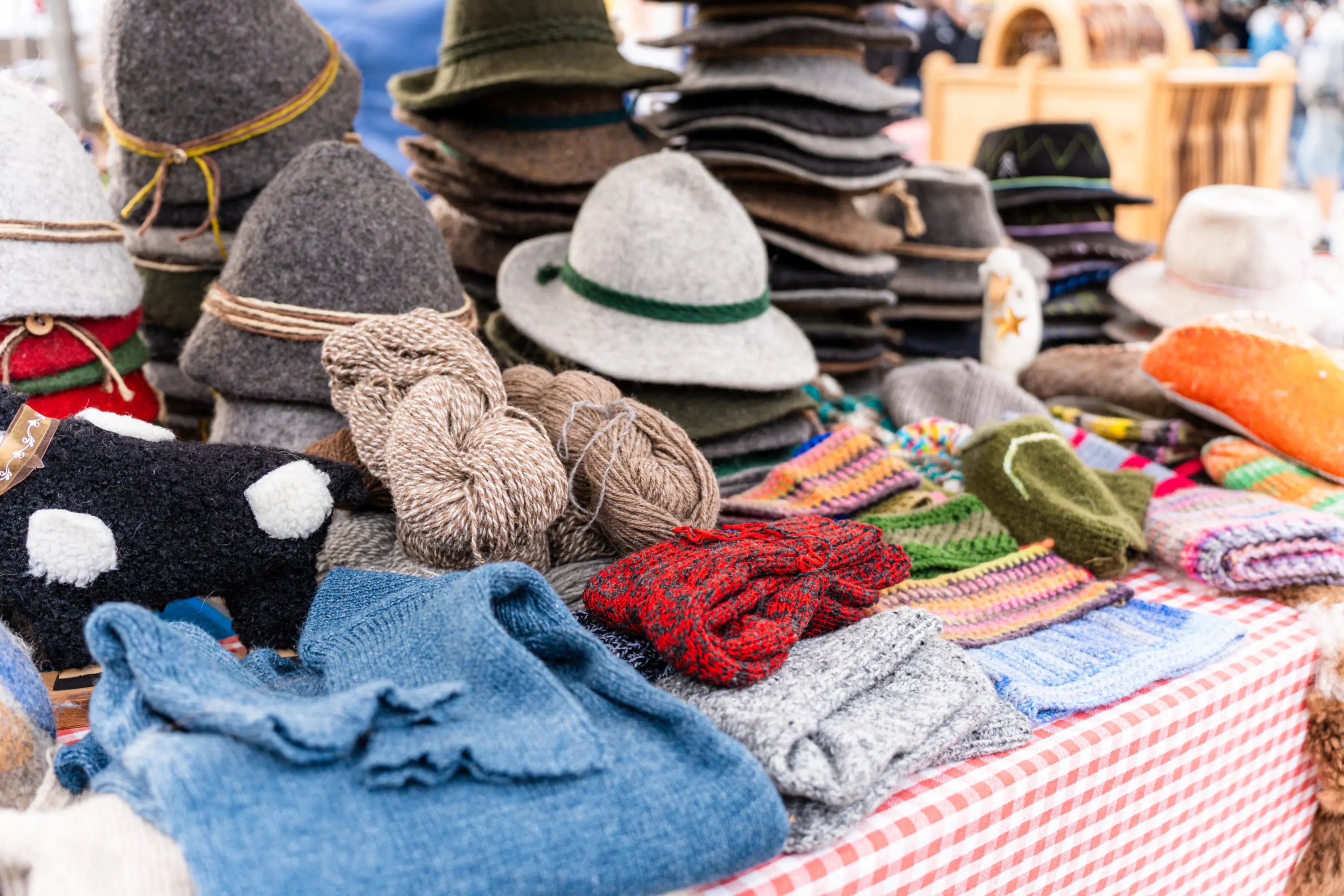 Cappelli di feltro, matasse di lana e capi fatti a maglia su un banco