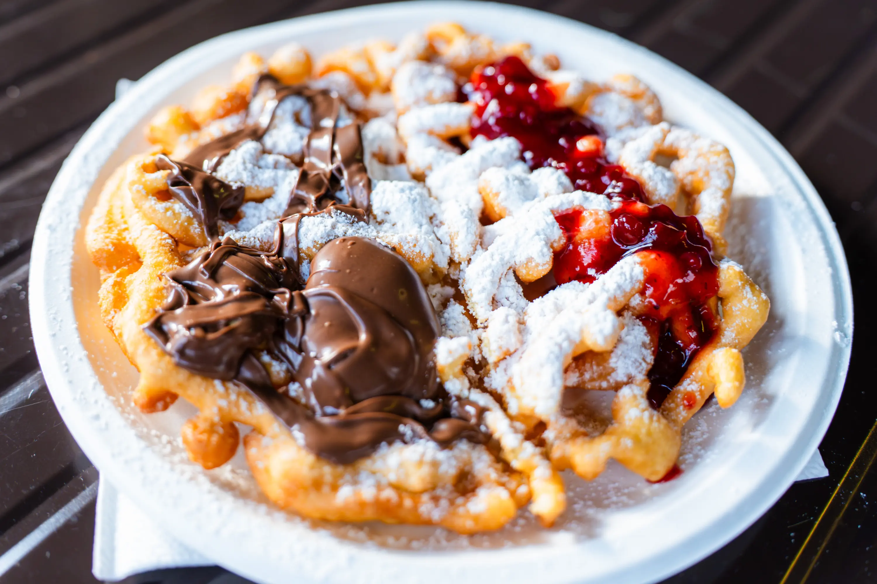 Uno strauben nel piatto con lo zucchero a velo, la crema al cioccolato e la marmellata rossa