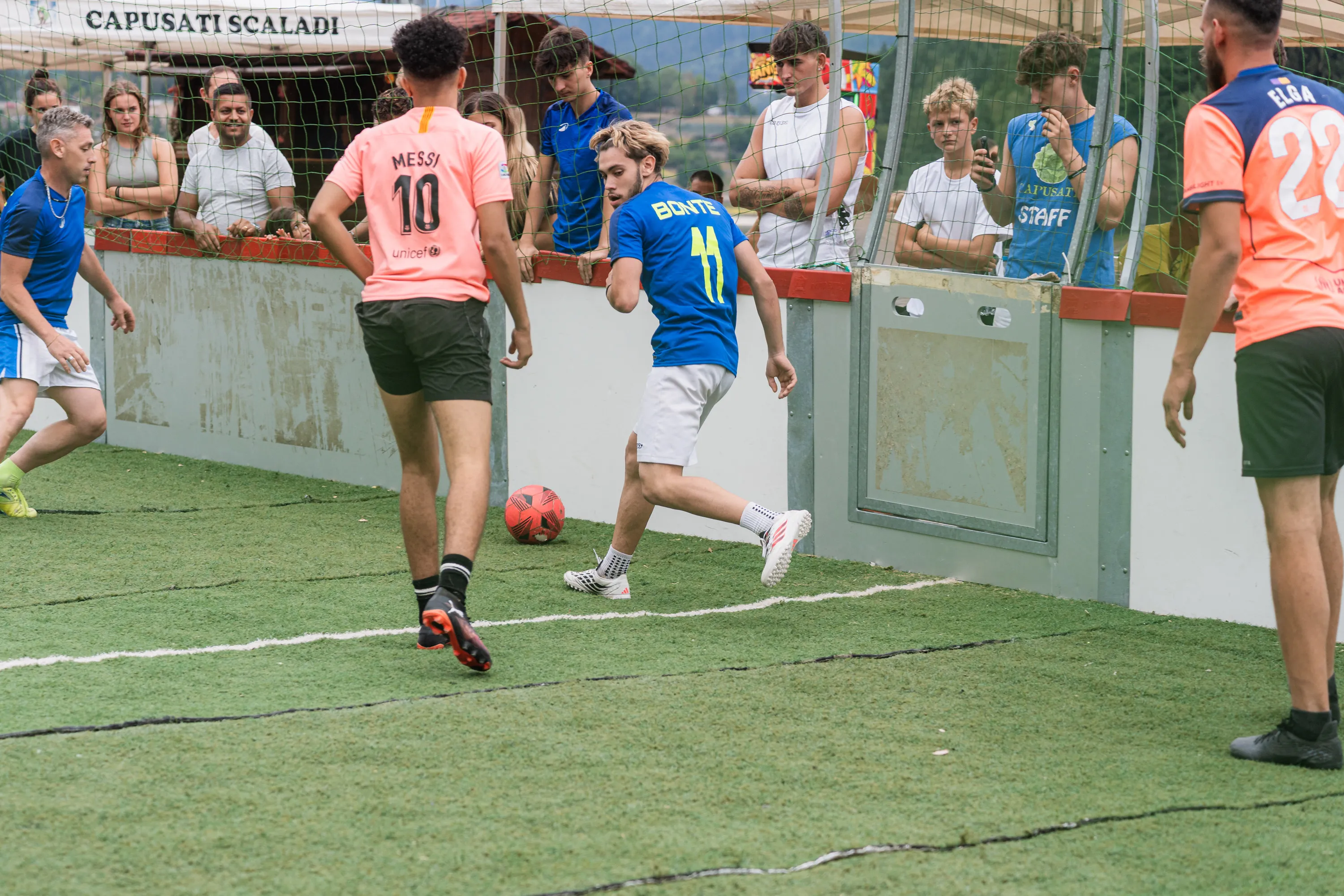 Una partita di calcio nel campetto recintato sul prato del festival