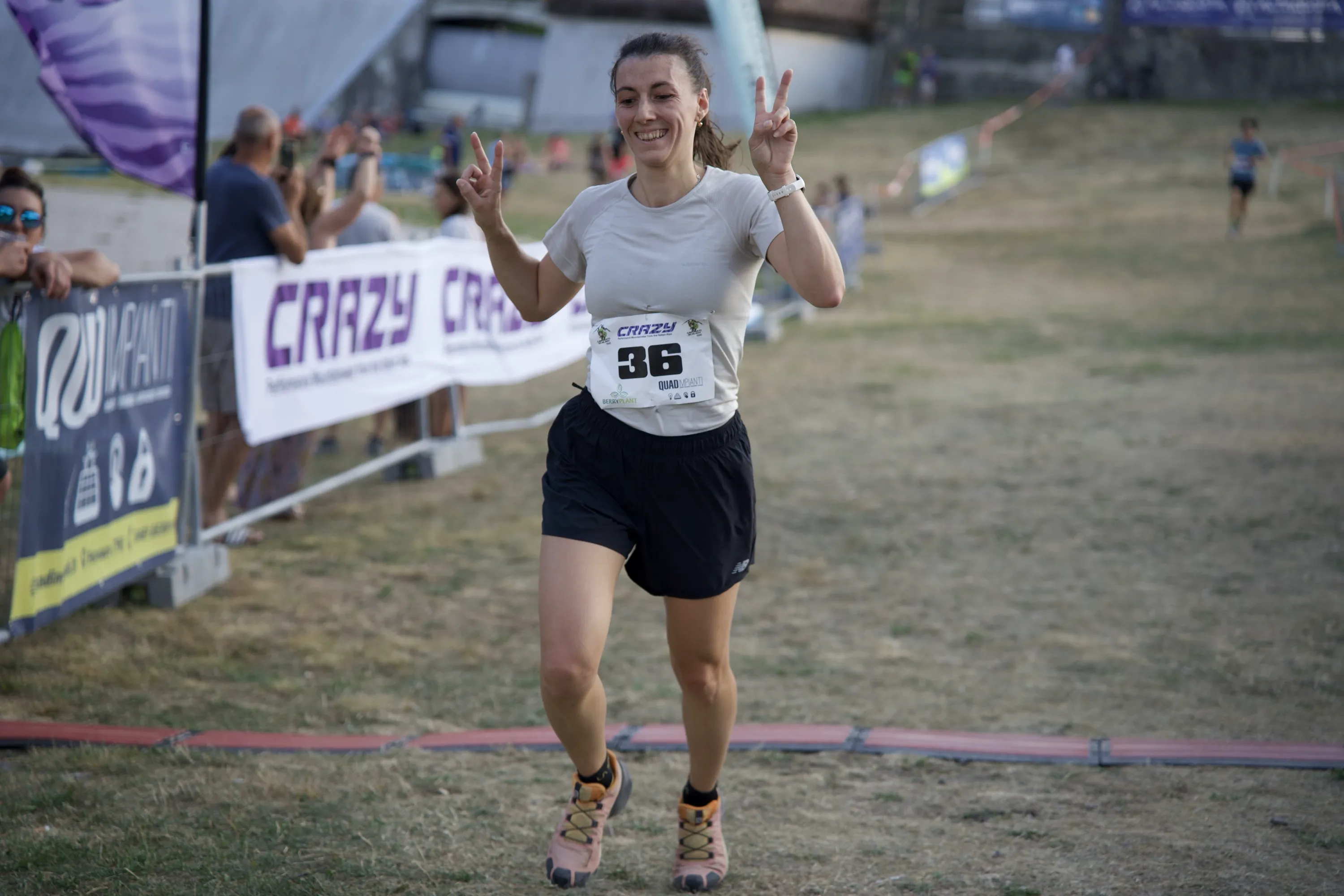 Un'atleta alza le dita in segno di vittoria arrivando al traguardo