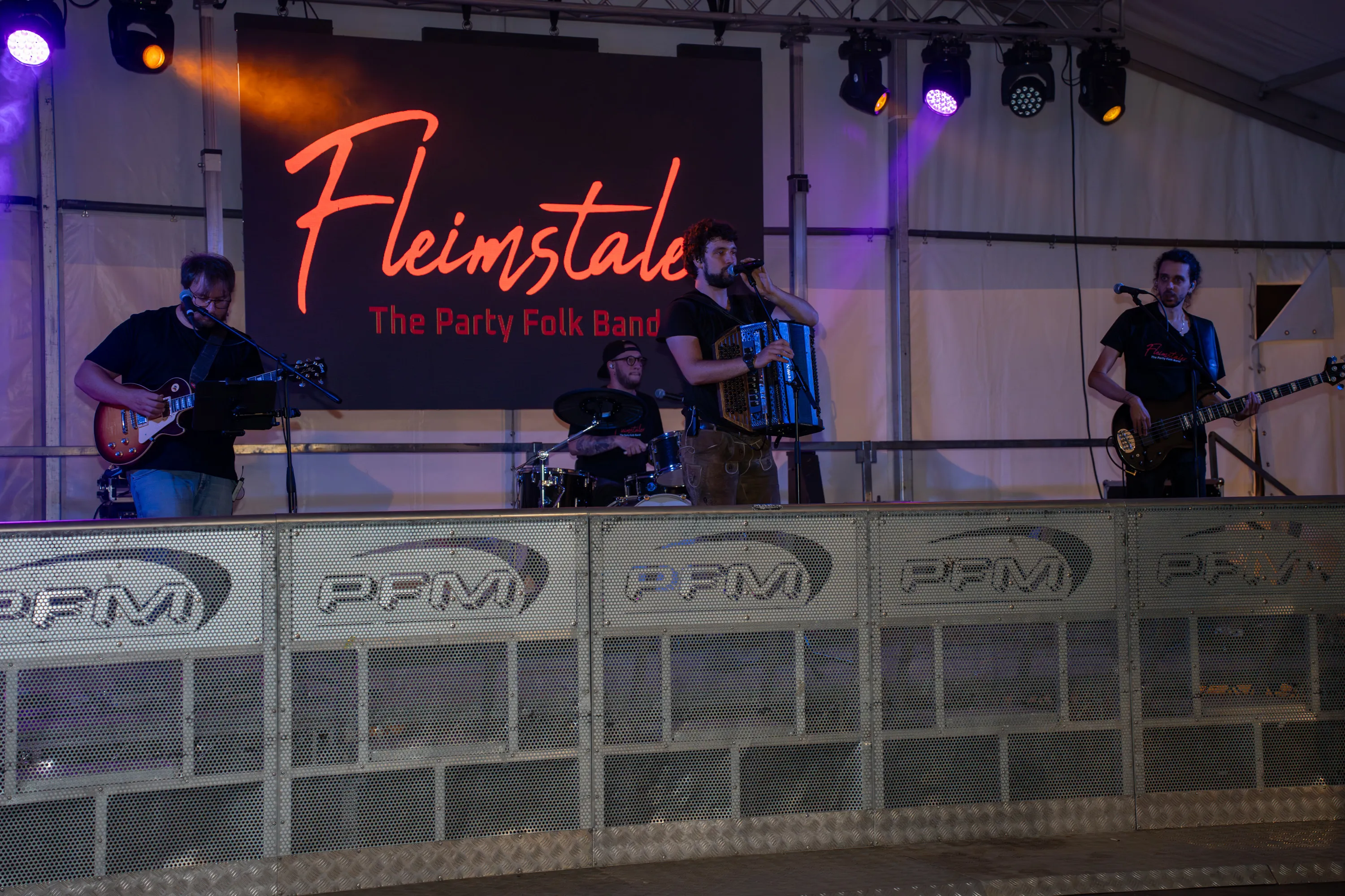 Il palco sotto il tendone con l'insegna al neon della band, la prima sera