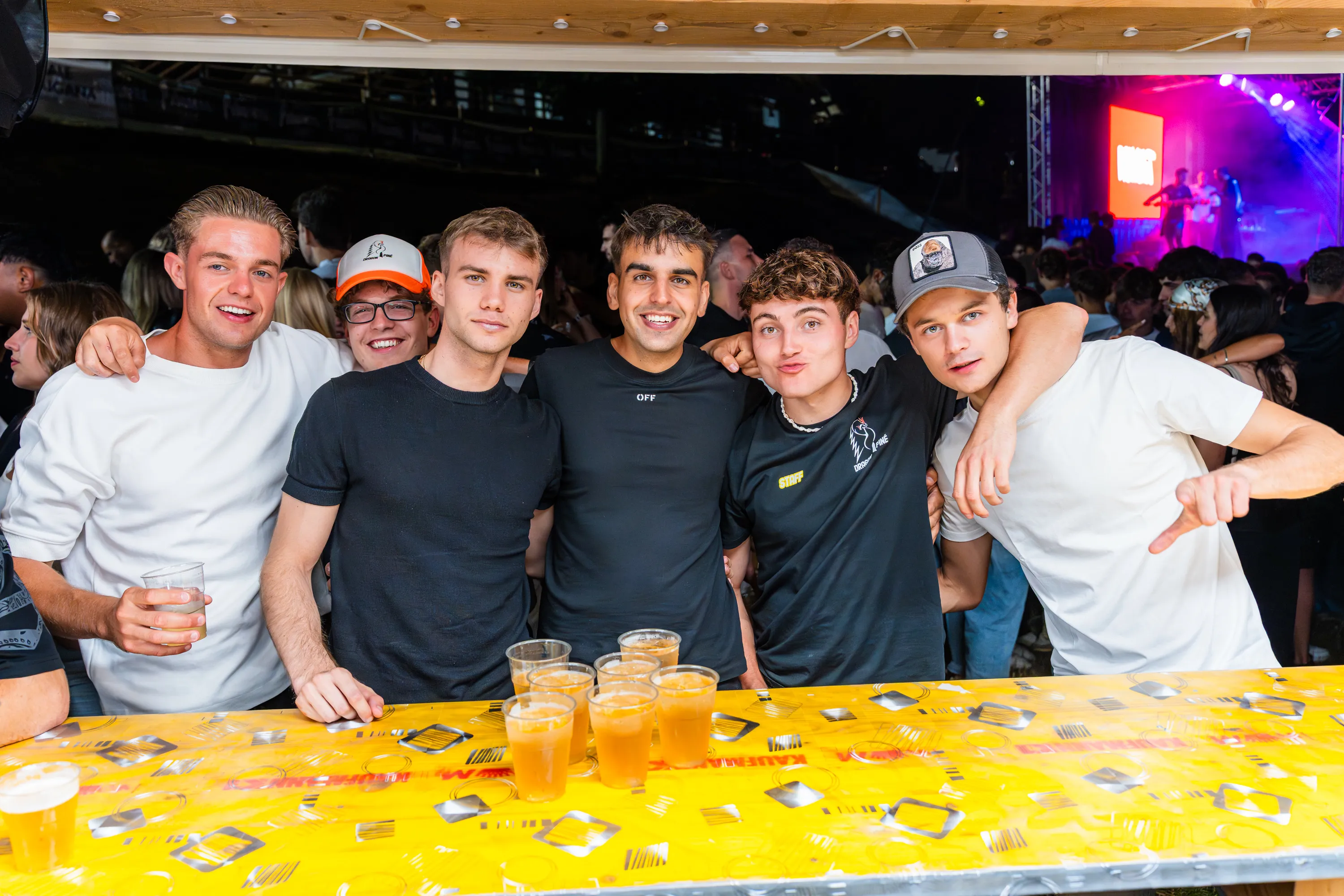 Un gruppo di ragazzi con i bicchieri al tavolo giallo della festa