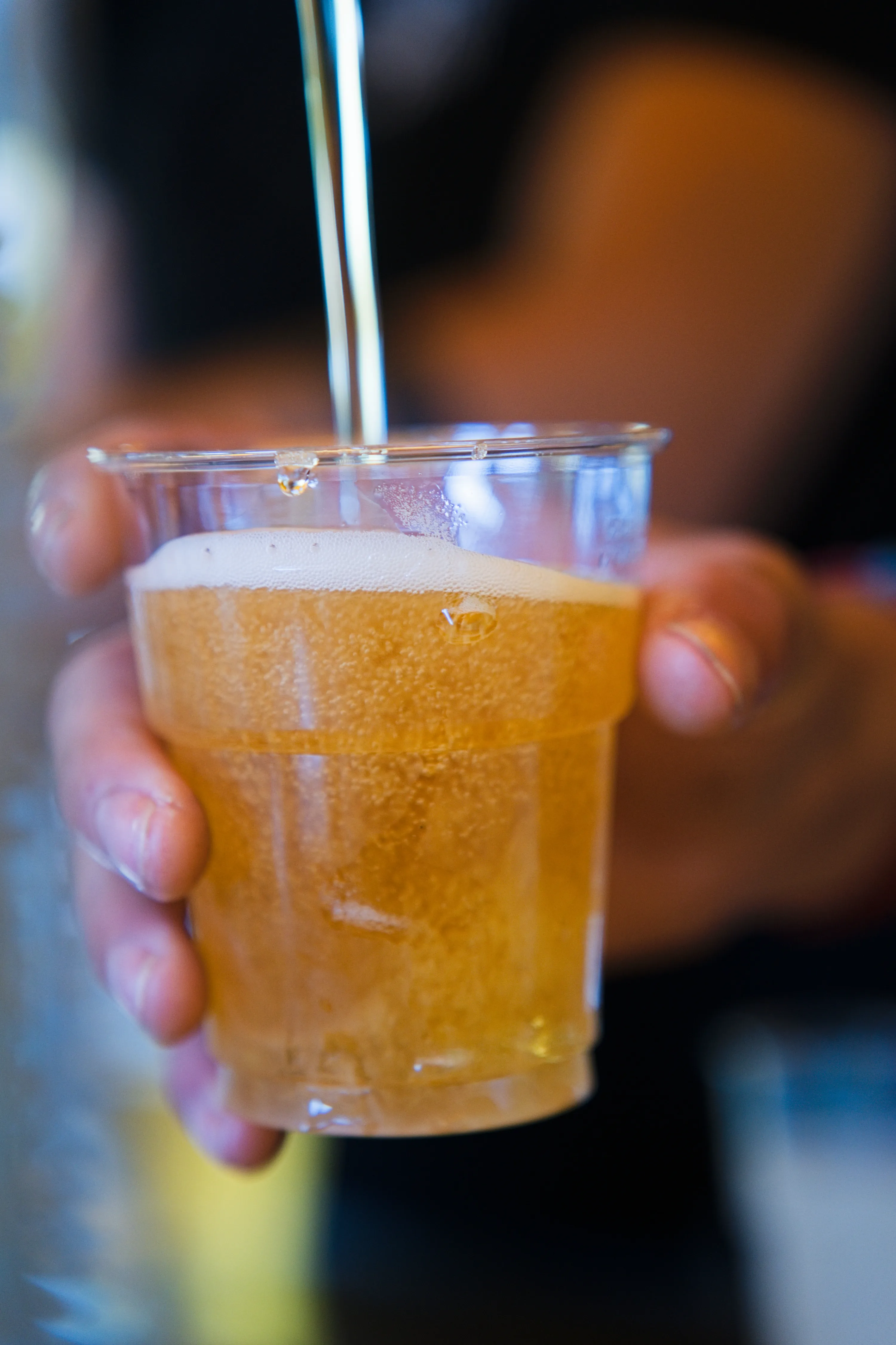 Un bicchiere di birra in primo piano, con la festa sfocata dietro