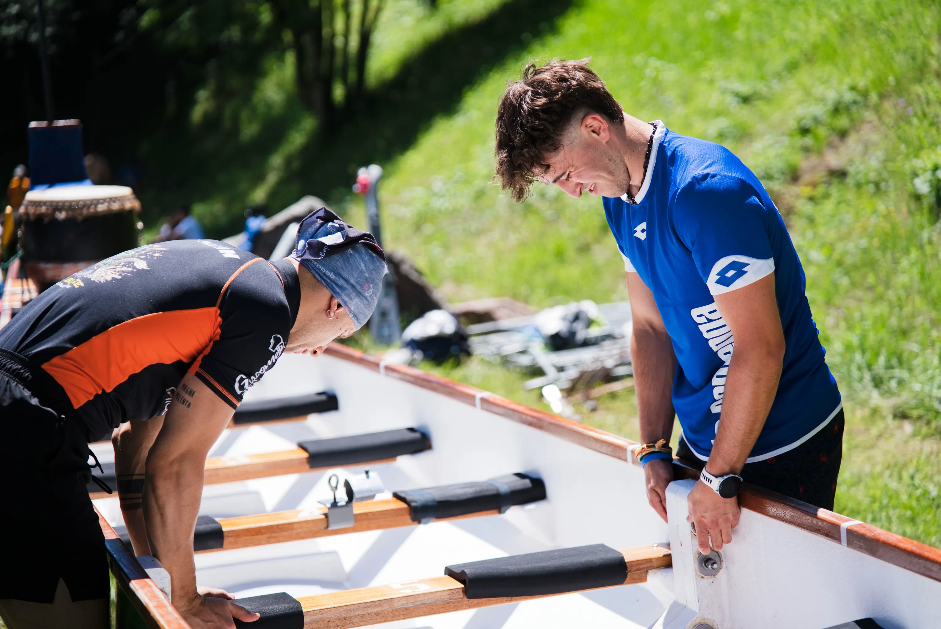 Un atleta si piega sulle pagaie allineate lungo la barca
