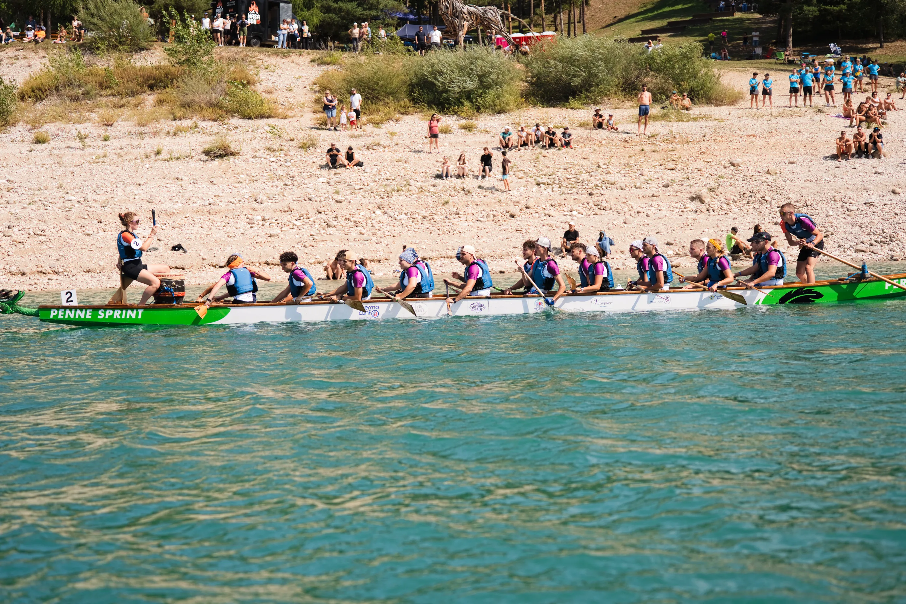 La riva di ghiaia bianca con il pubblico e una barca in gara