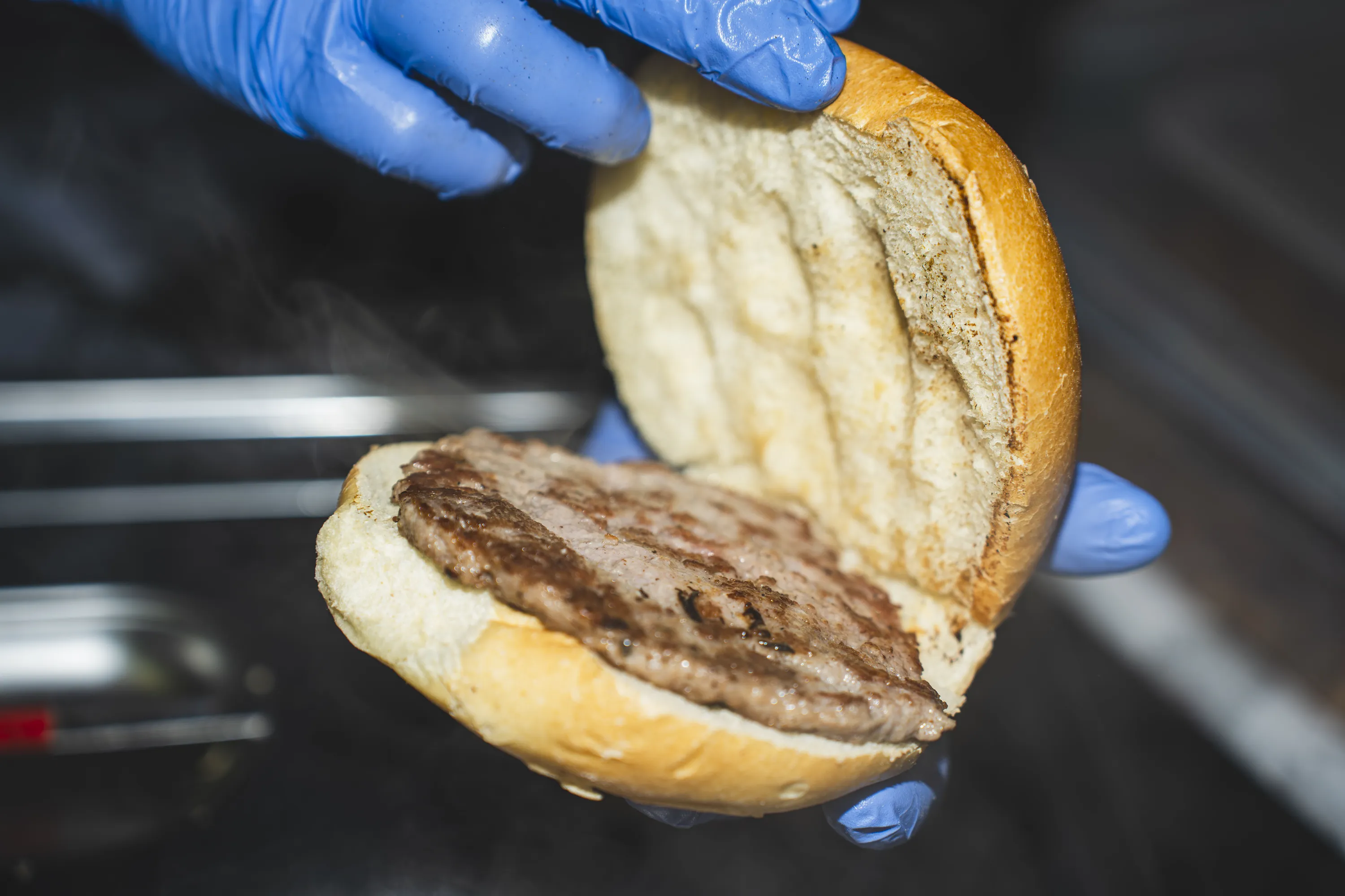 Le mani di un volontario preparano un panino con la salsiccia