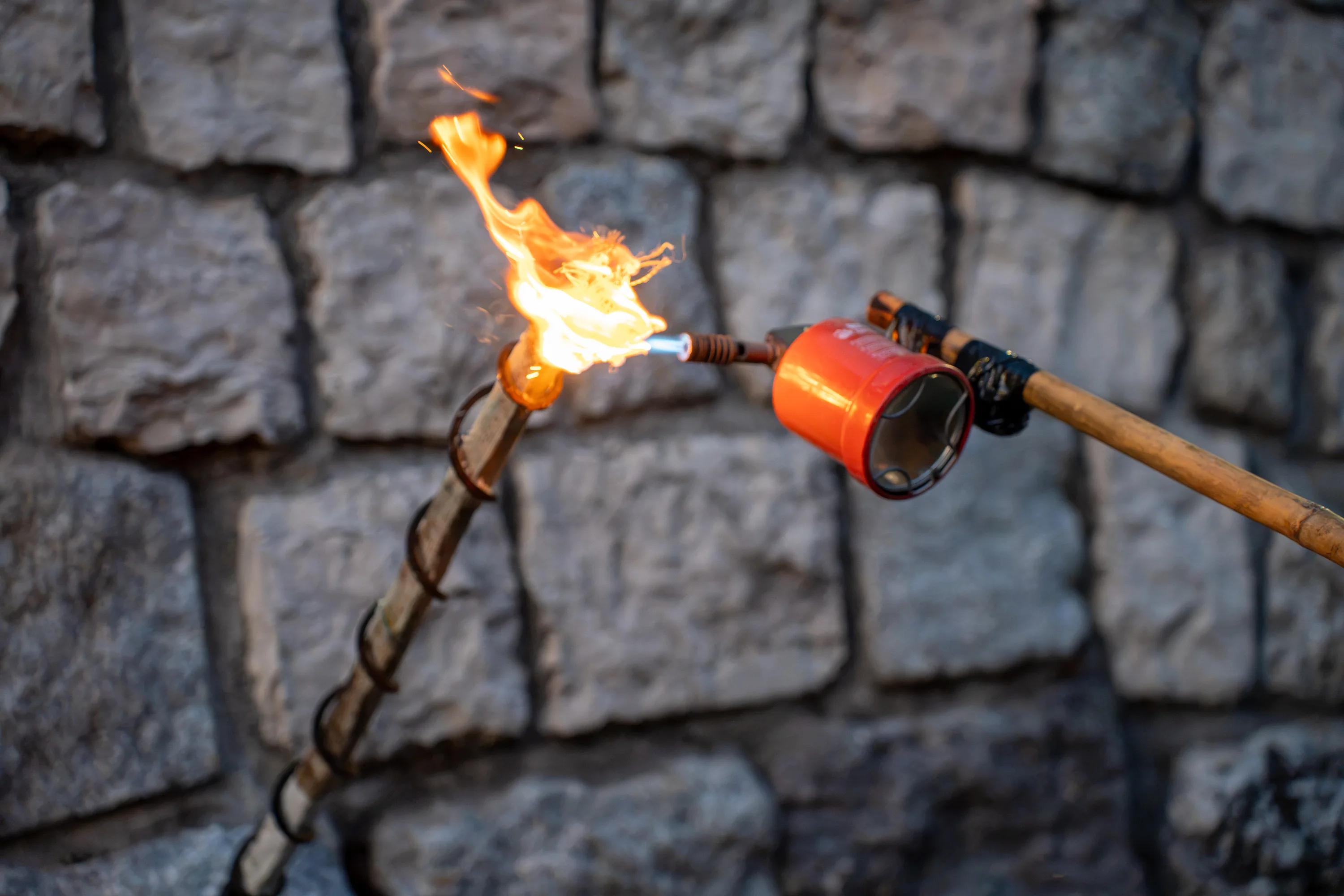 Una fiaccola sul muro di pietra prende fuoco dal cannello in cima all'asta