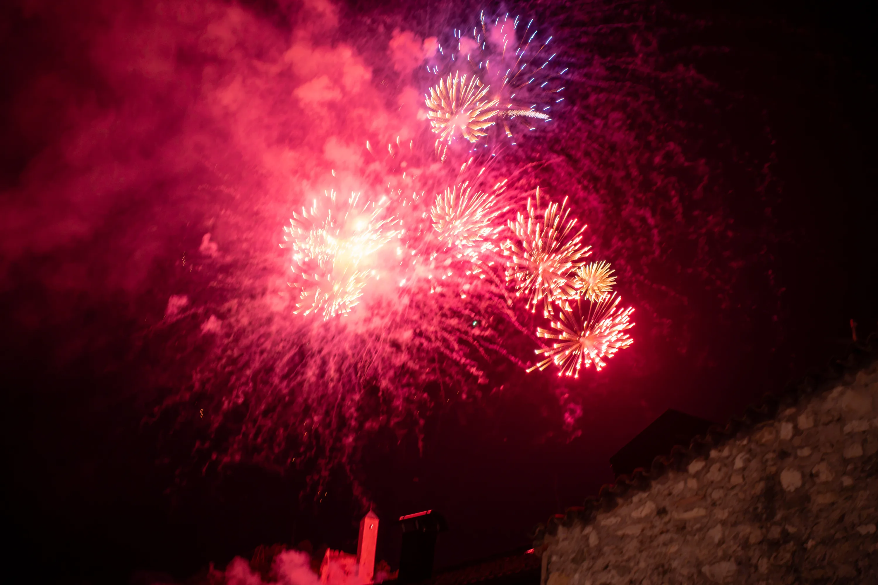 I fuochi d'artificio rossi sopra i tetti del paese