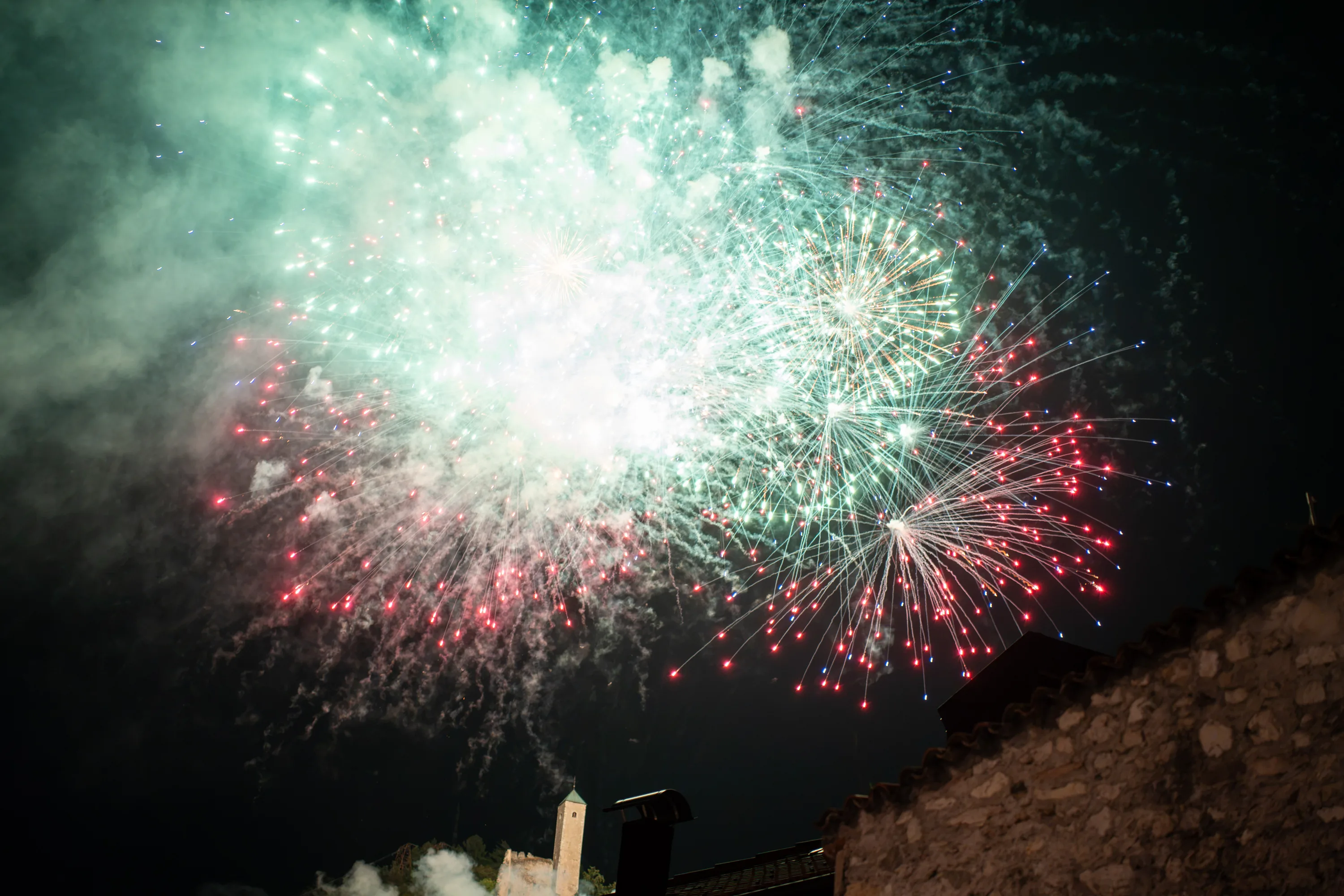 I fuochi d'artificio verdi e bianchi sopra i tetti, nel fumo