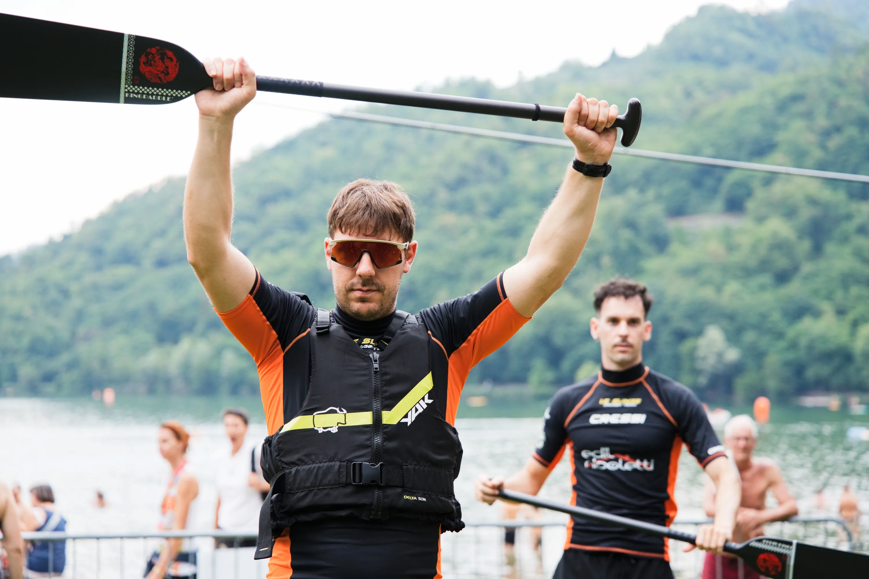 Un atleta alza la pagaia con le braccia spalancate dopo l'arrivo