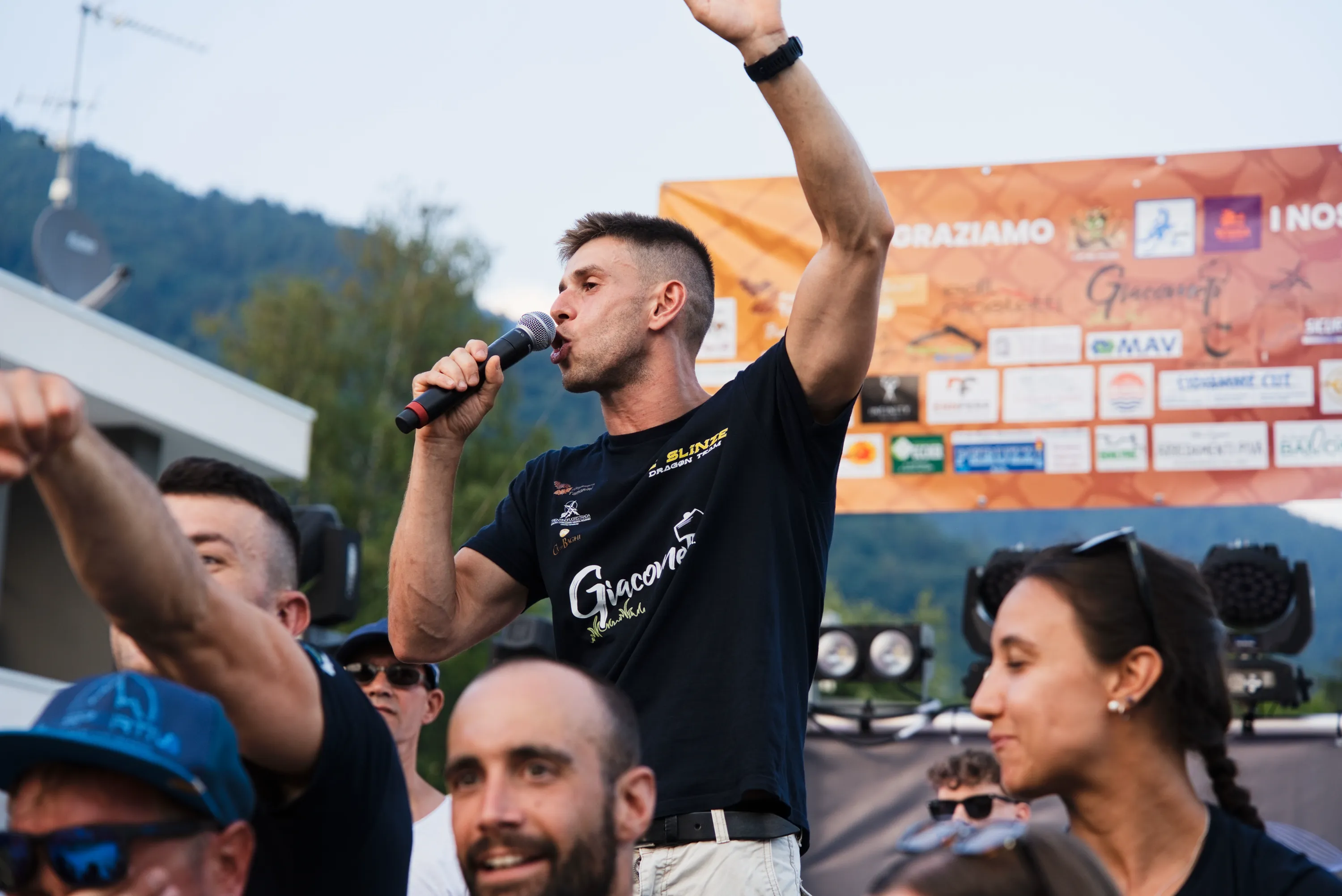 Lo speaker al microfono davanti al cartellone degli sponsor
