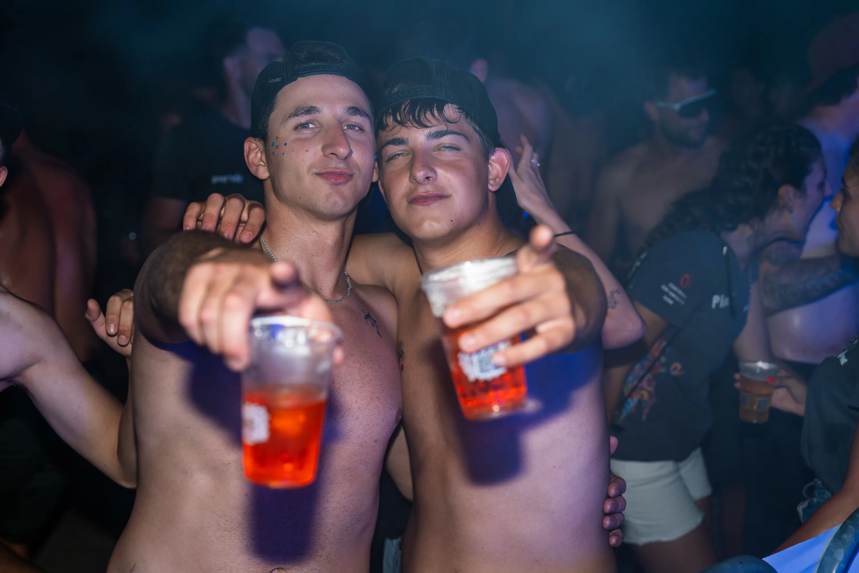 Due ragazzi con i bicchieri in mano in mezzo alla folla notturna
