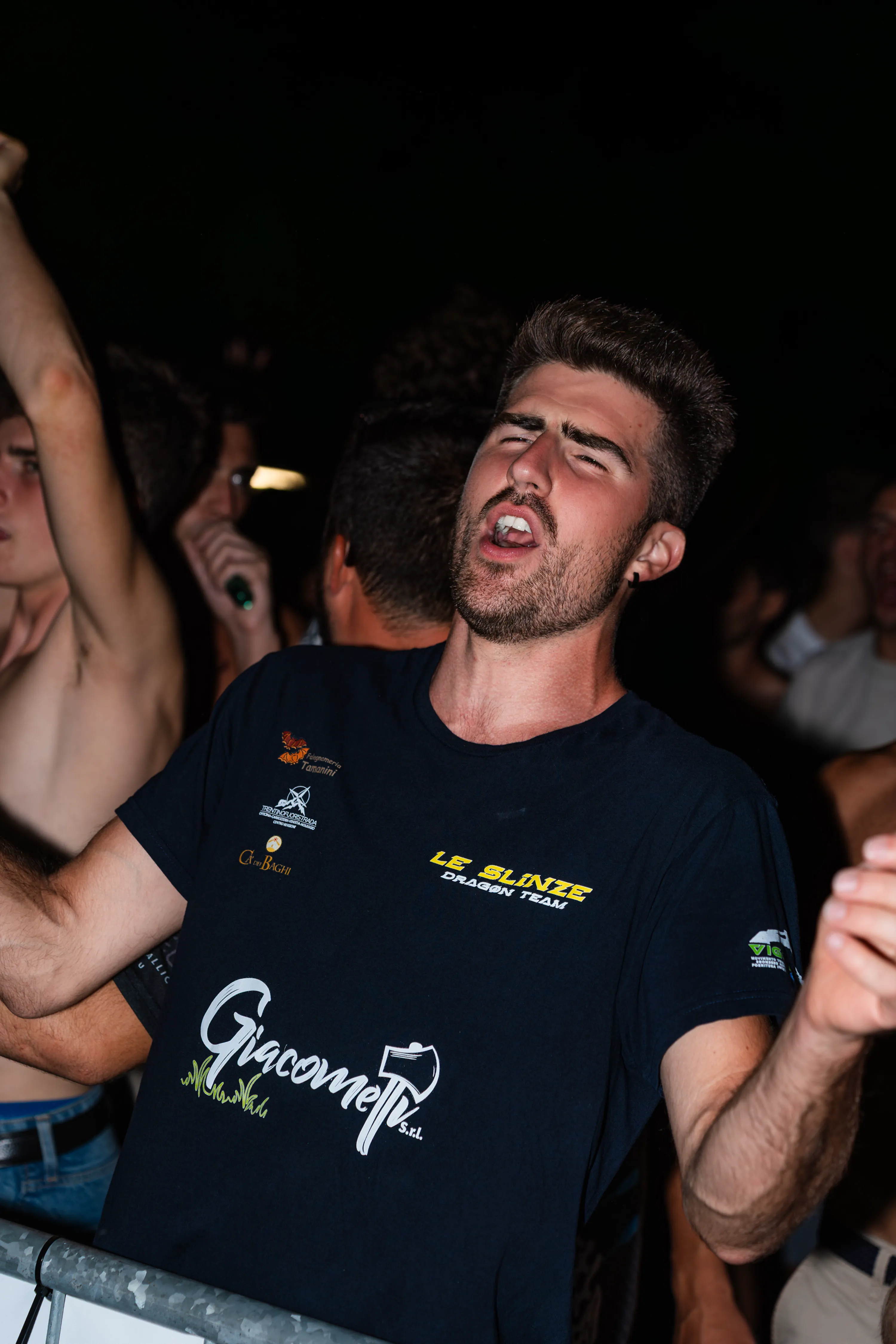 Un ragazzo canta in mezzo alla folla, al buio