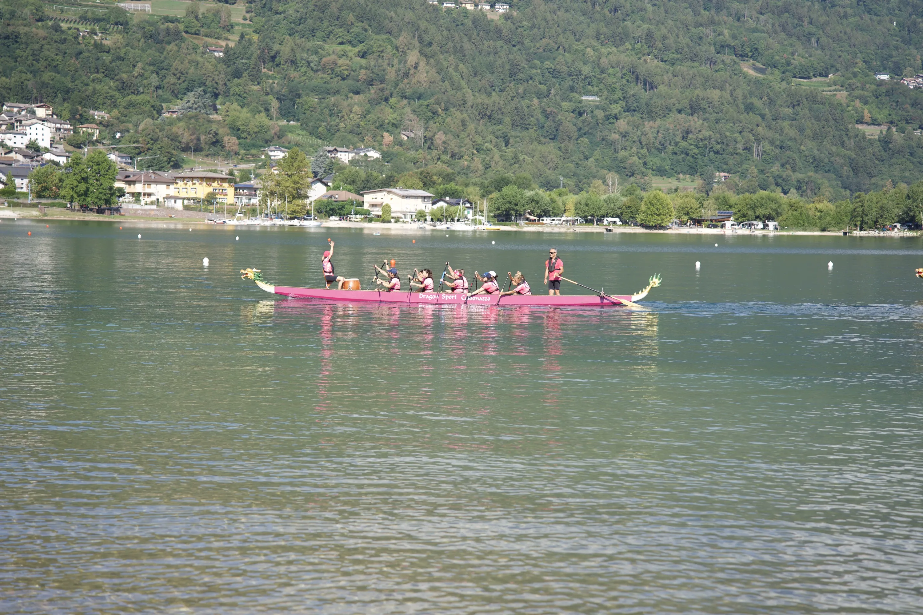 Una barca drago con equipaggio in rosa attraversa il lago di Caldonazzo