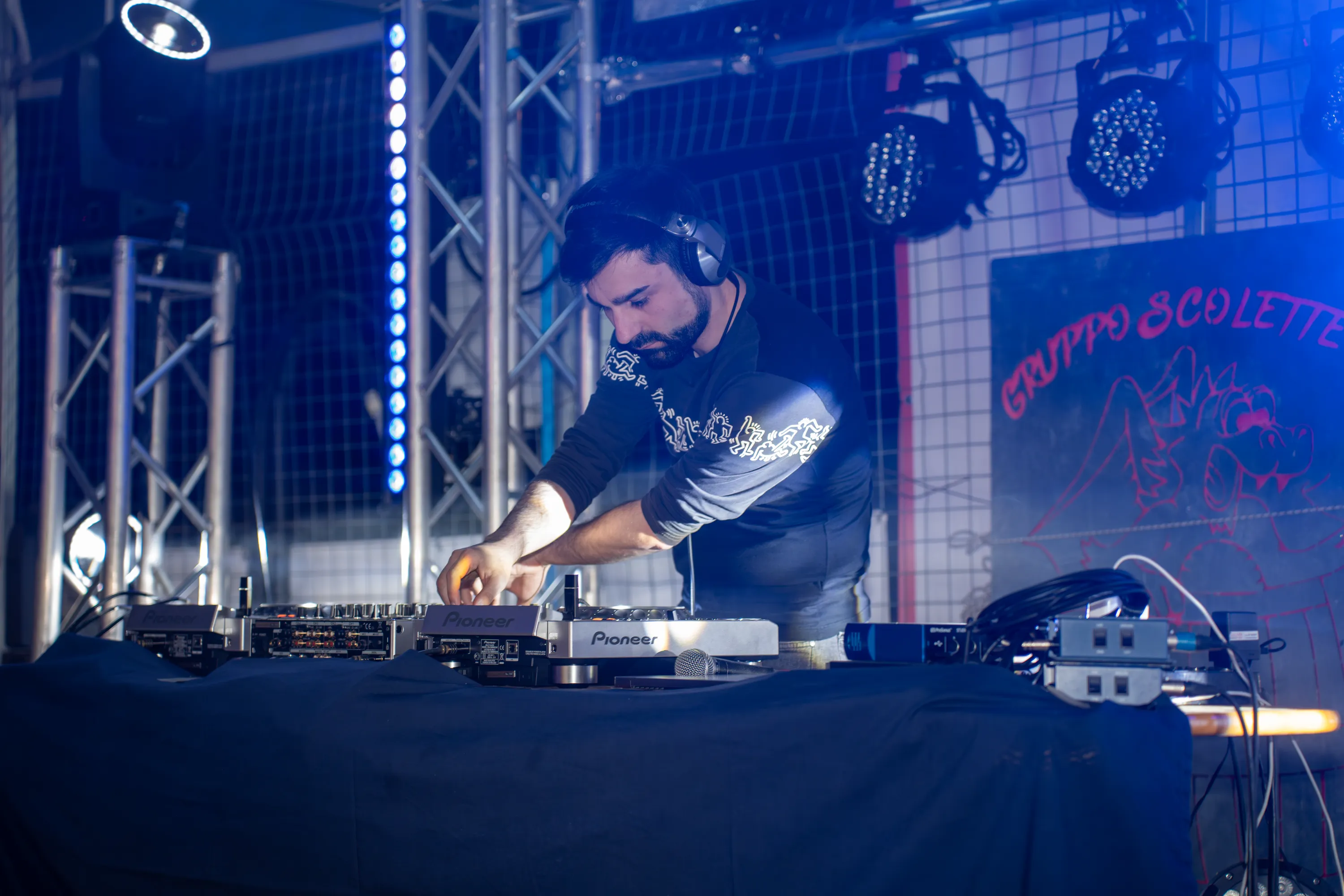 Il dj alla consolle davanti alla parete di luci blu