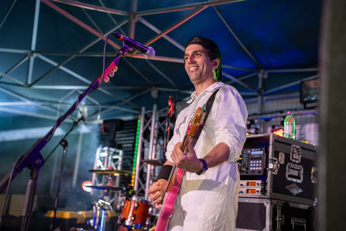 Il cantante della band suona il basso sotto il gazebo del palco, con il microfono davanti