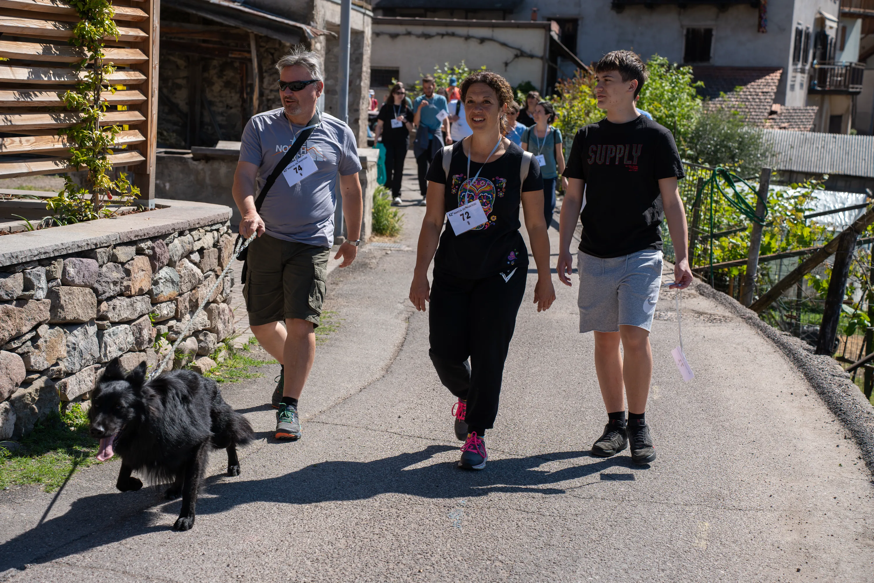 La strada del paese durante la marcia della domenica, con i camminatori e un cane