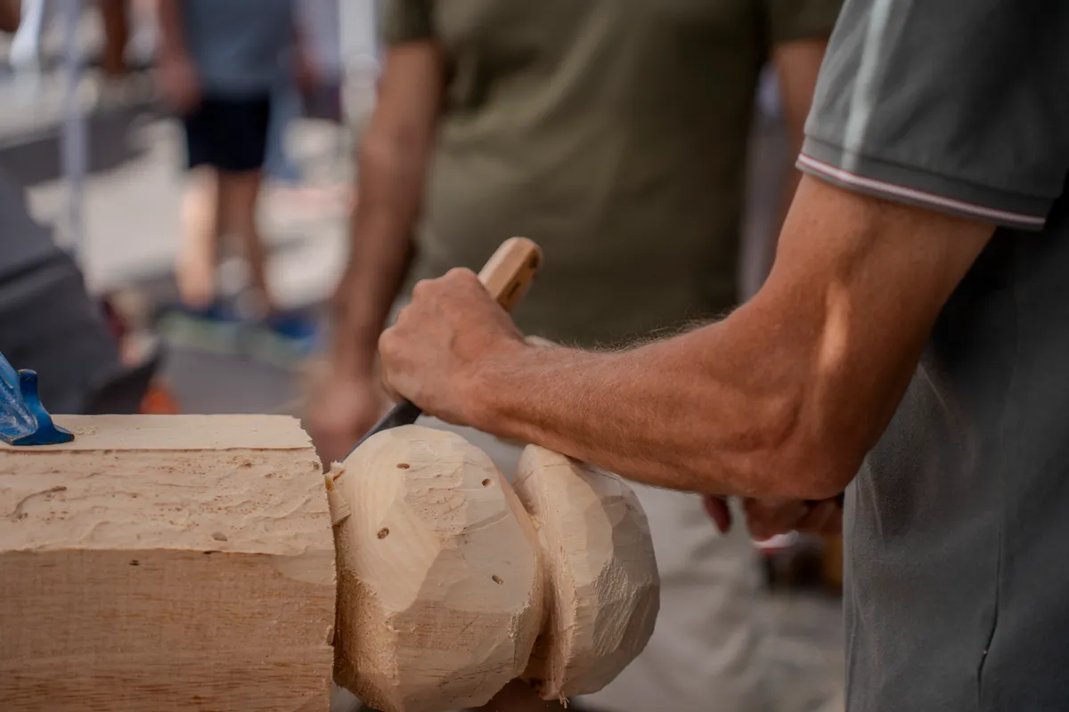 Le mani di un artigiano scolpiscono con lo scalpello un tronco di legno