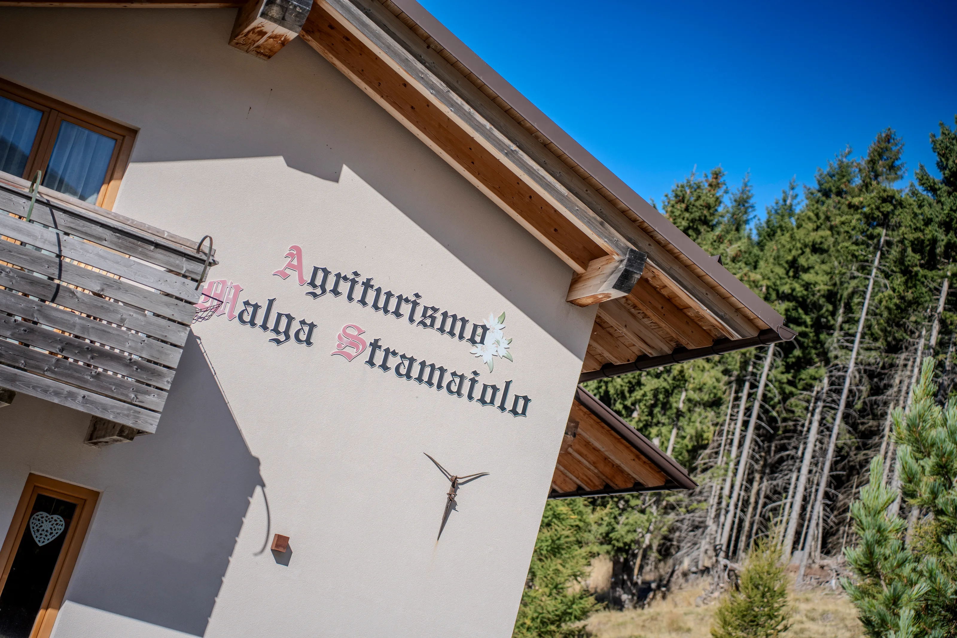 L'insegna dipinta dell'Agriturismo Malga Stramaiolo sulla facciata, vista dal basso