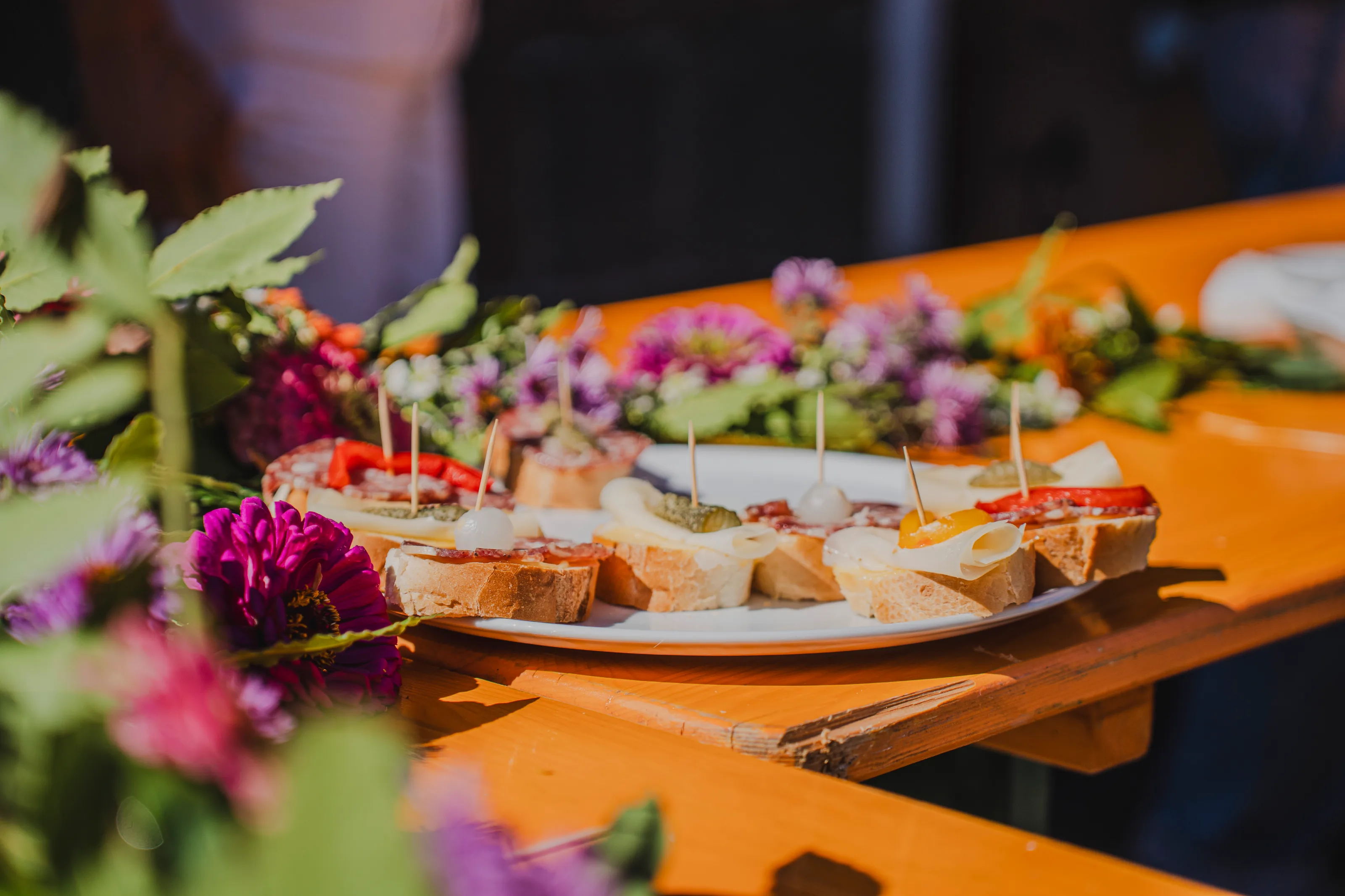 Tartine e stuzzichini decorati con fiori su una tavola arancione