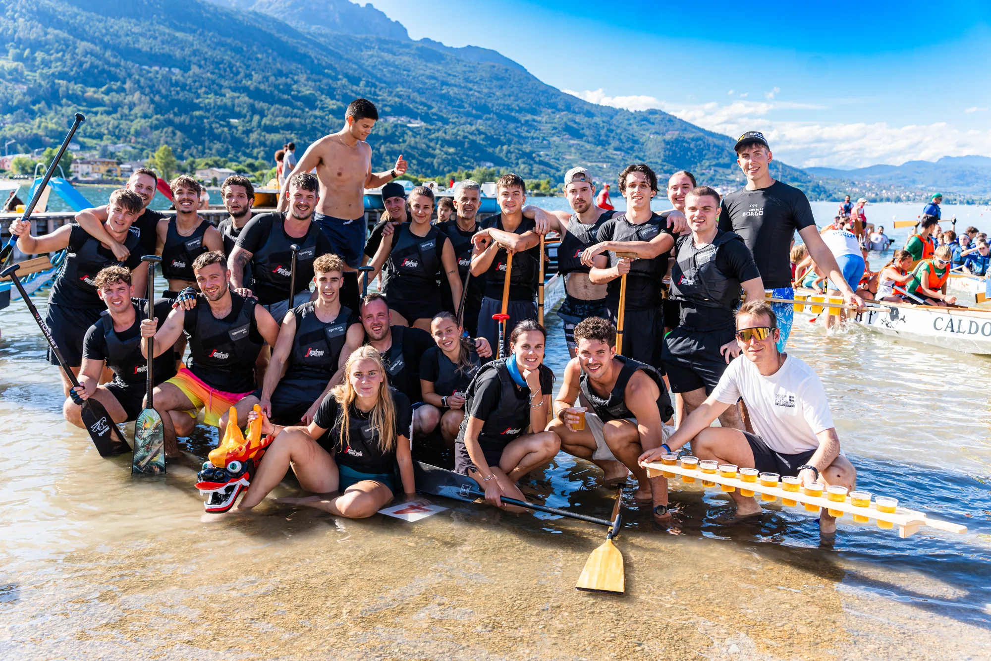 Una squadra al completo in posa attorno alla barca sulla riva del lago di Caldonazzo