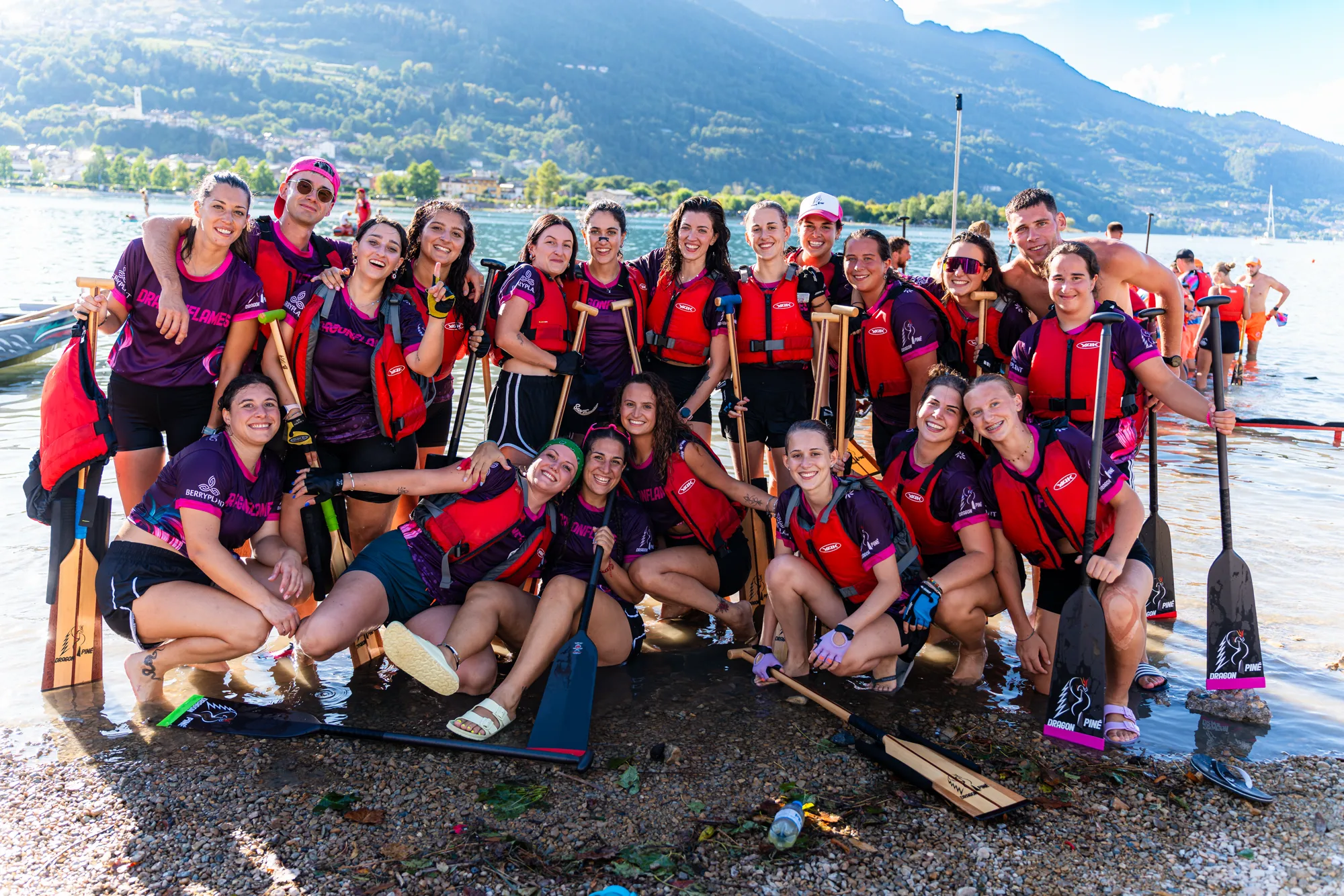 Una squadra in divisa rosa e viola in posa con le pagaie alzate