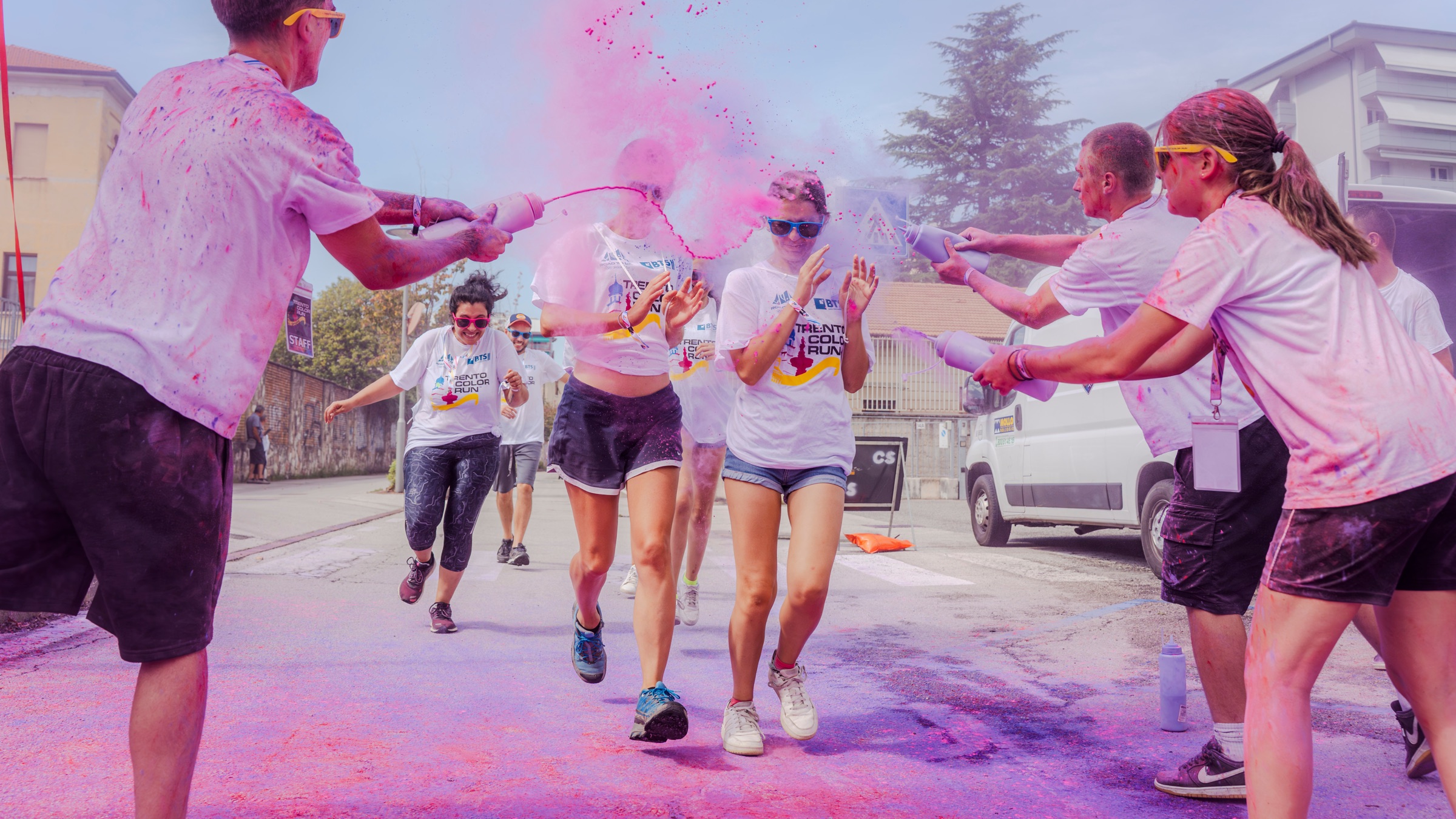 Corridori della Trento Color Run avvolti da nuvole di polvere colorata rosa e viola