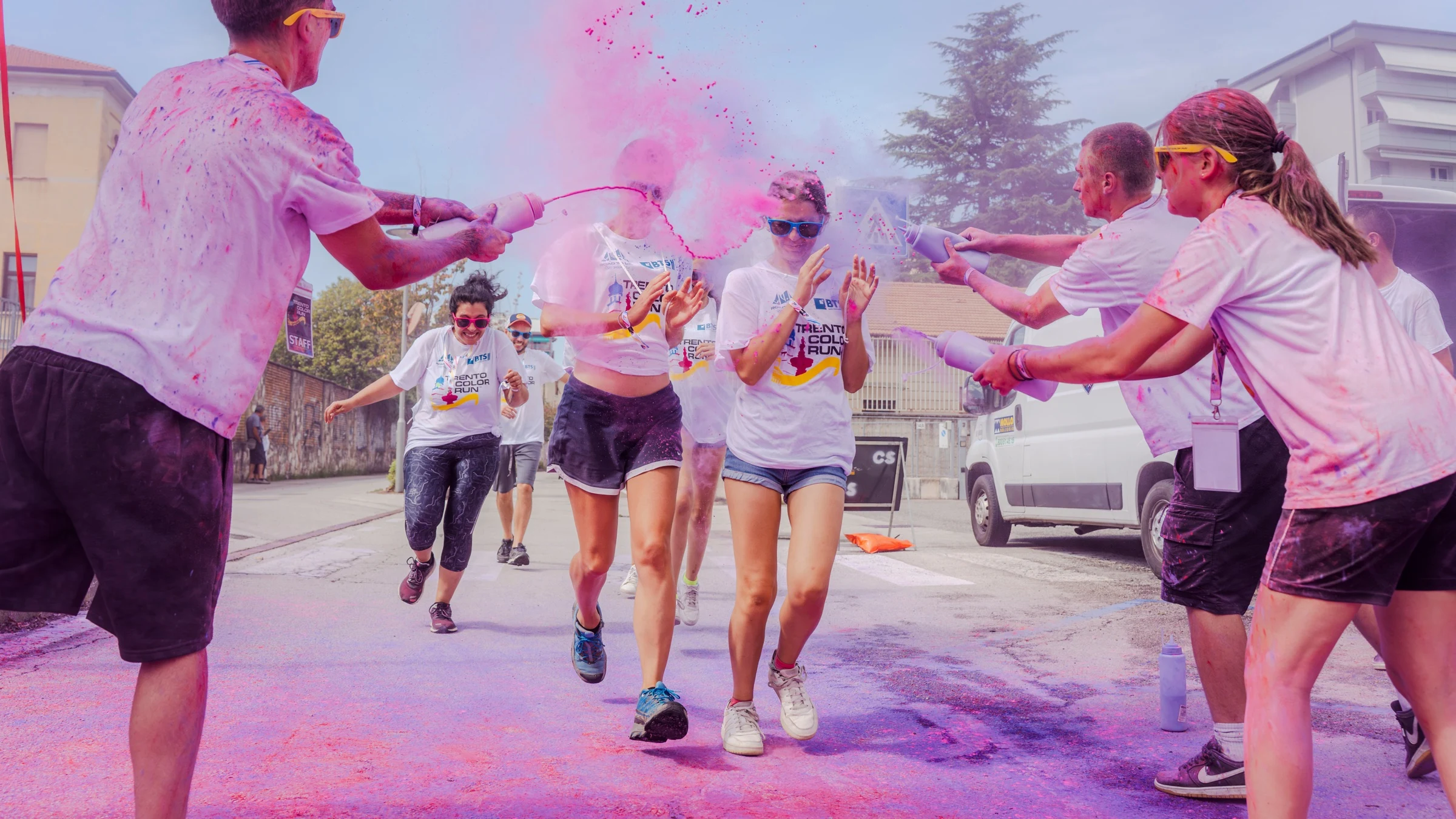 Corridori della Trento Color Run avvolti da nuvole di polvere colorata rosa e viola