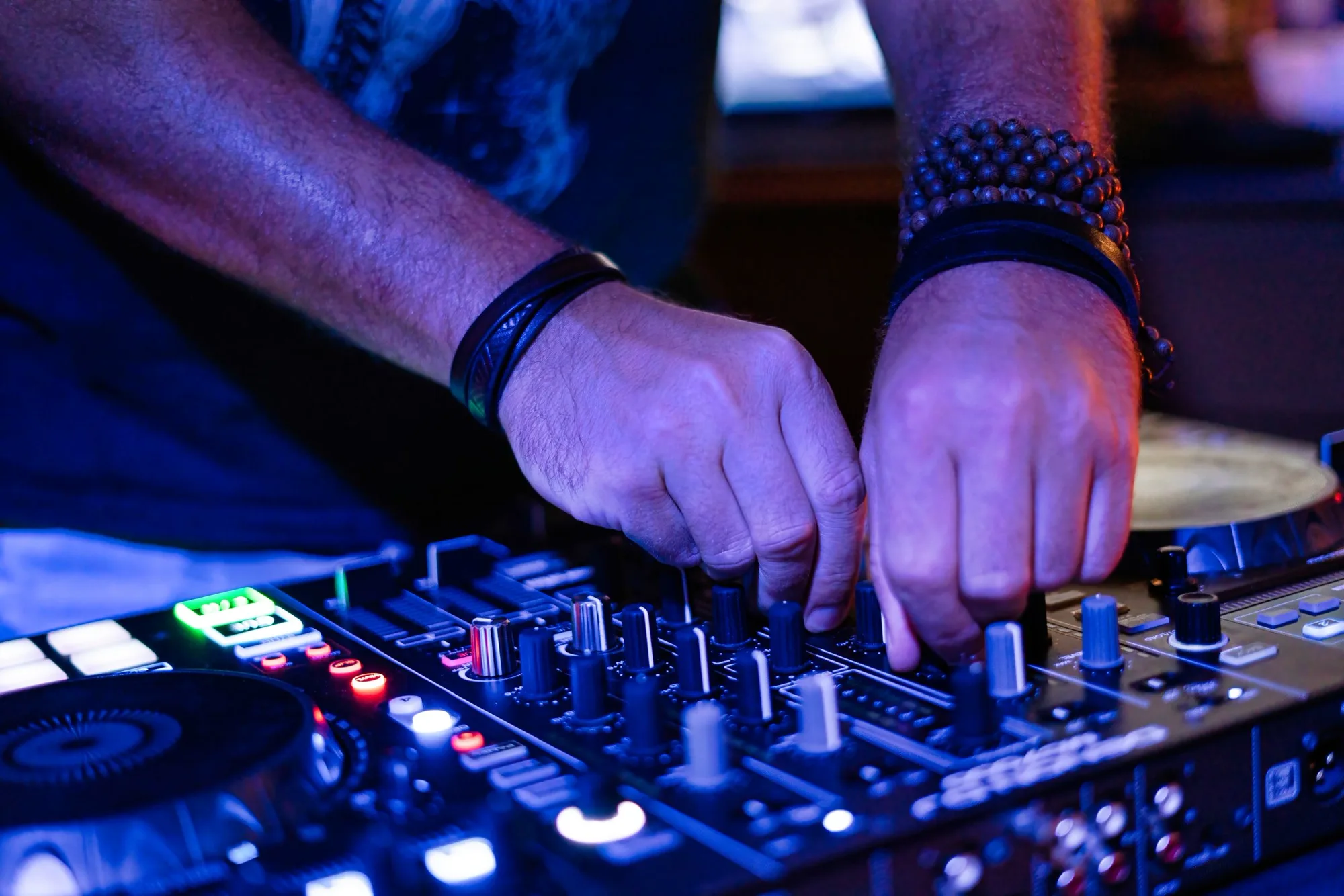 Le mani di un dj sulla consolle, illuminate di blu