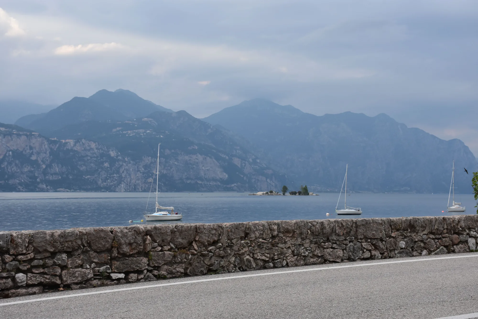 Il lago di Garda con le barche a vela e le montagne sul fondo