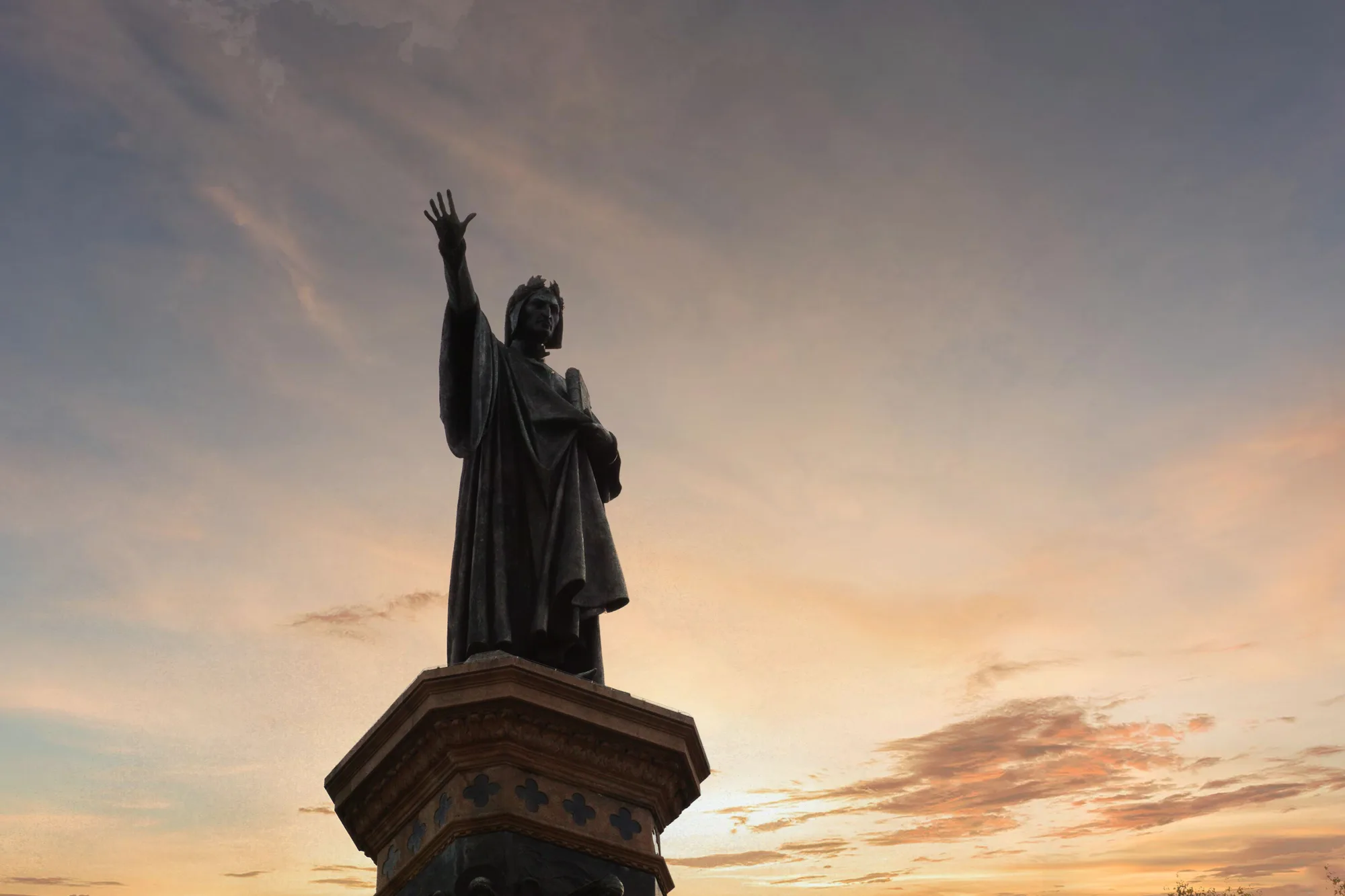La statua di Dante Alighieri controluce al tramonto, a Trento