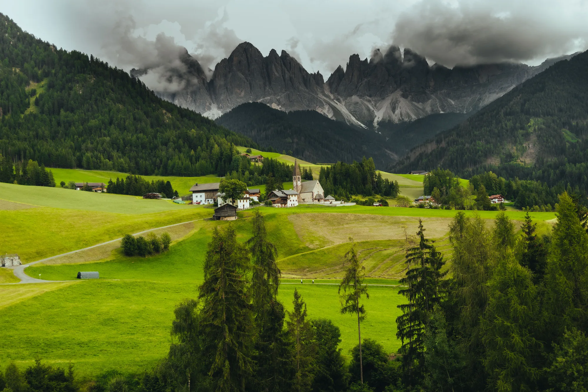 Un paese di montagna con le cime e il verde, sotto un cielo di nuvole