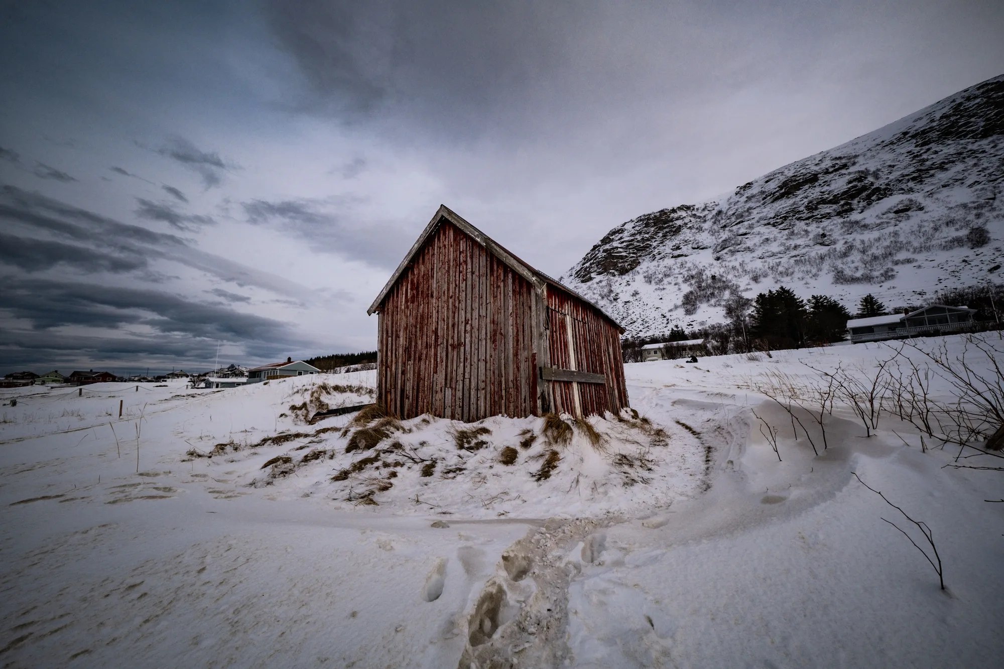 Un fienile di legno in un campo innevato, sotto un cielo d'inverno