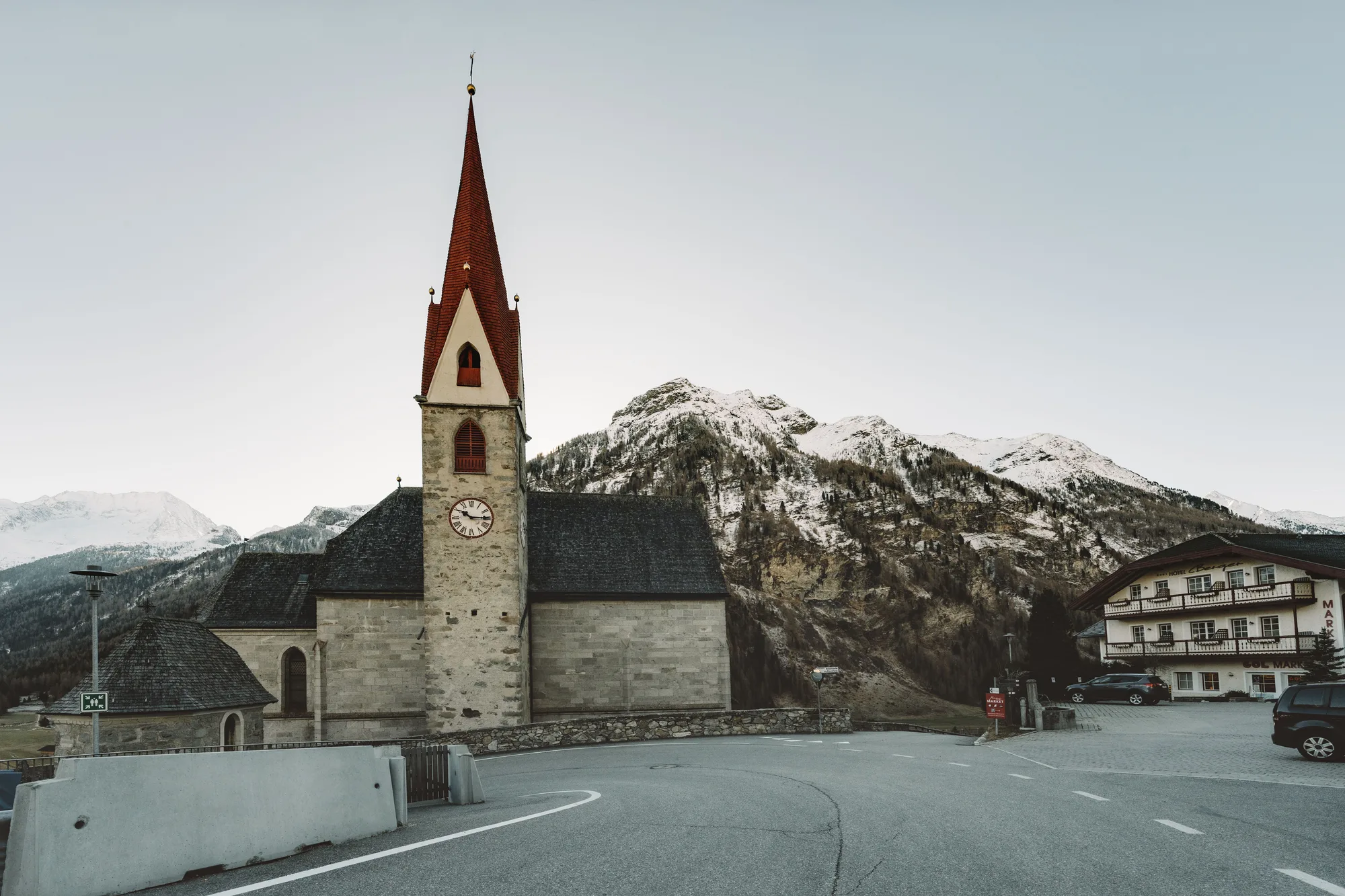 Una chiesa in un paese di montagna, con le cime innevate dietro