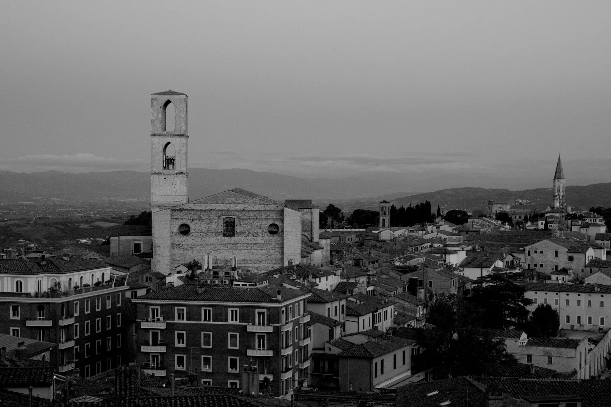 Veduta aerea in bianco e nero di una città italiana, con l'architettura medievale e i campanili