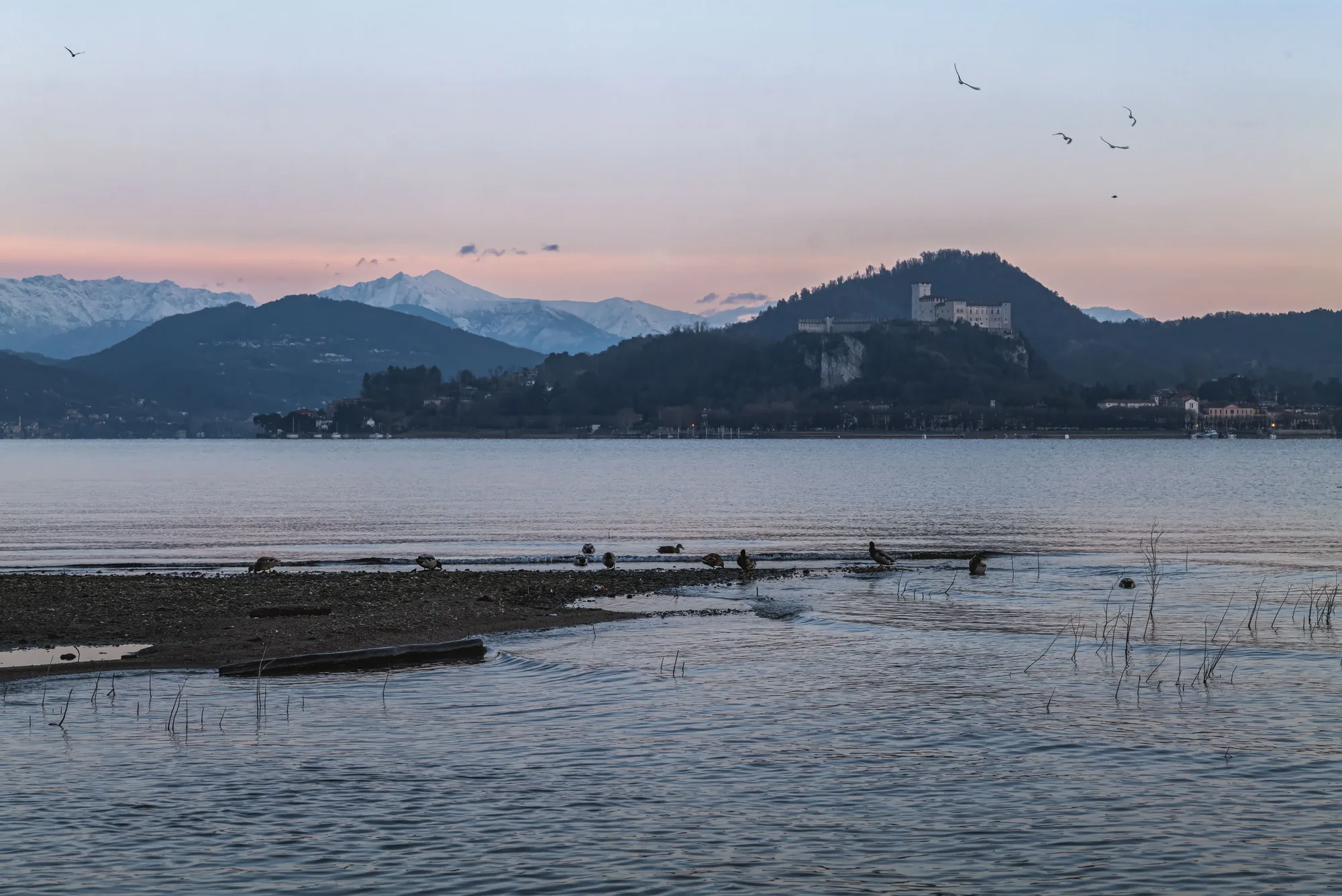 Un lago al tramonto con le montagne e un castello sul fondo